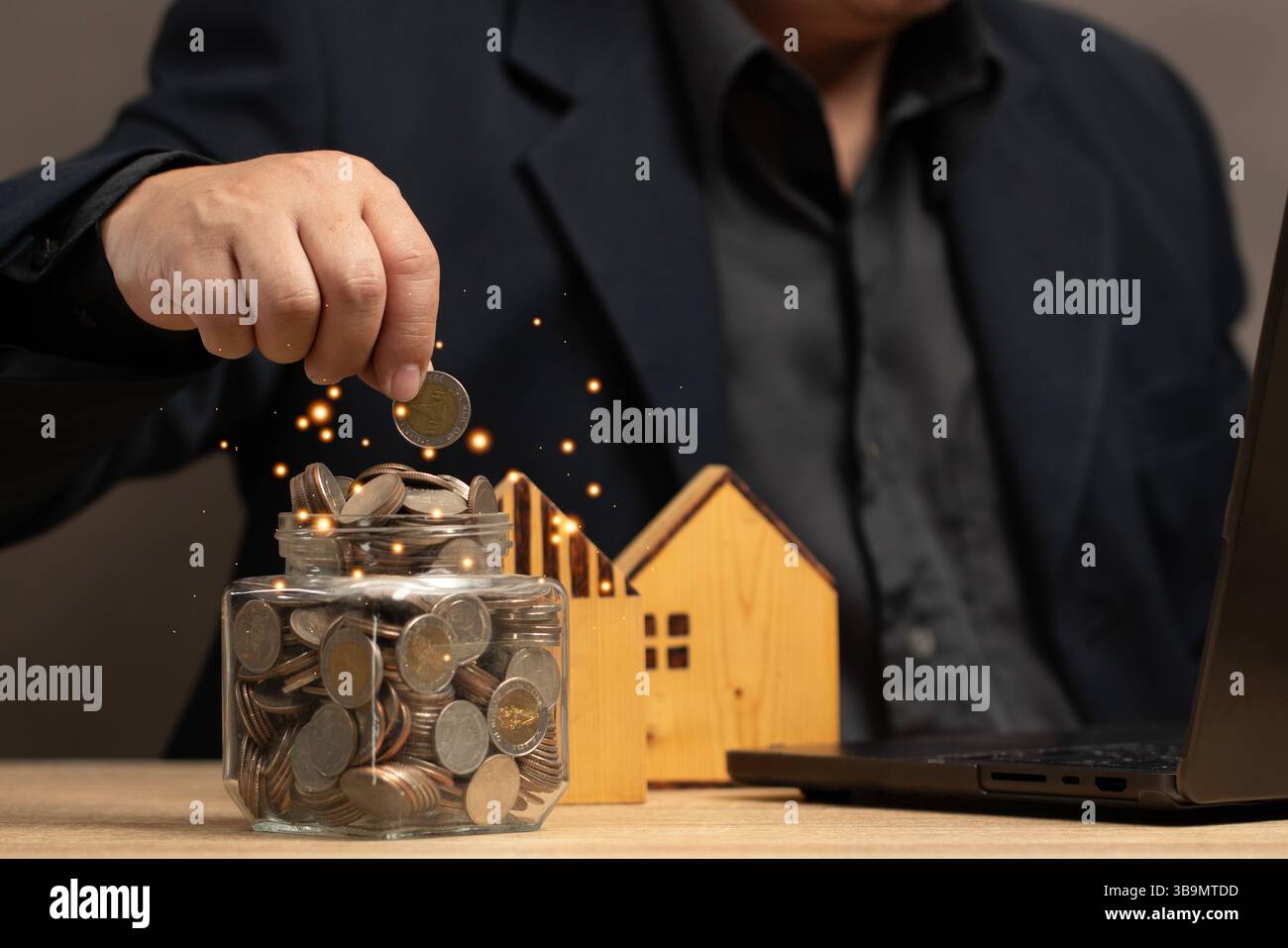 Uomo che mette le monete in un barattolo pieno di risparmi. L'obiettivo dell'investimento immobiliare e dell'utilizzo della tecnologia per la gestione finanziaria e il processo decisionale informato Foto Stock