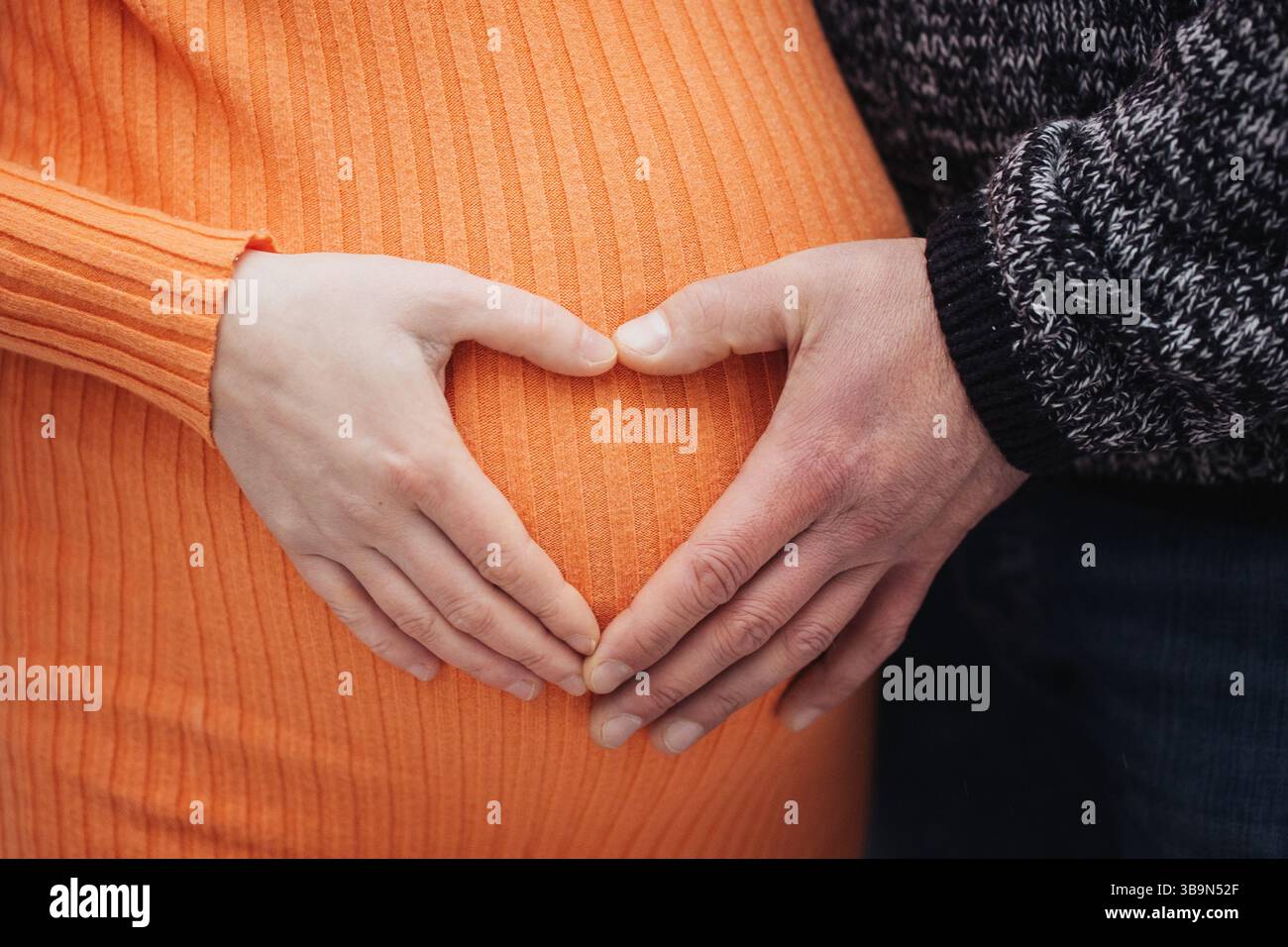 Coppia incinta mani cuore. Uomo e donna sulla pancia. Maternità amore e cura. Famiglia che aspetta un bambino. Felice momento di gravidanza. Foto Stock
