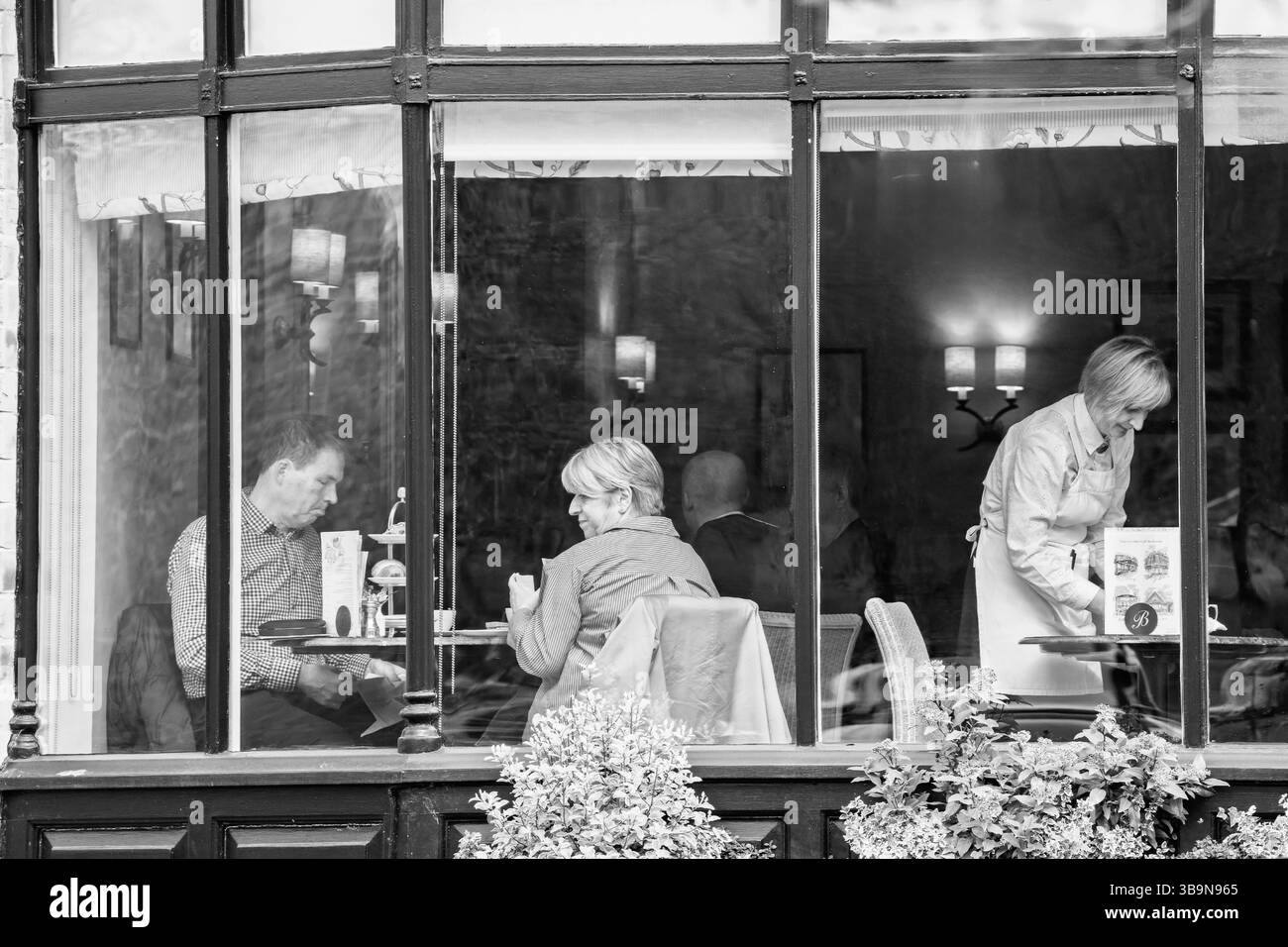 I clienti in un Bettys Cafe Tearooms vicino a una finestra stanno assaporando il tè Harrogate, Yorkshire, Regno Unito. Foto Stock