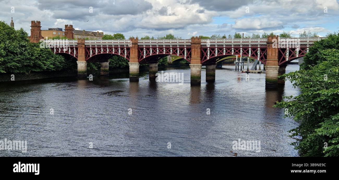Il Ponte Vecchio di Glasgow in una giornata estiva, circondato da lussureggianti alberi verdi e riflesso nelle calme acque del fiume Clyde. - Immagine stock catturata con smartphone
