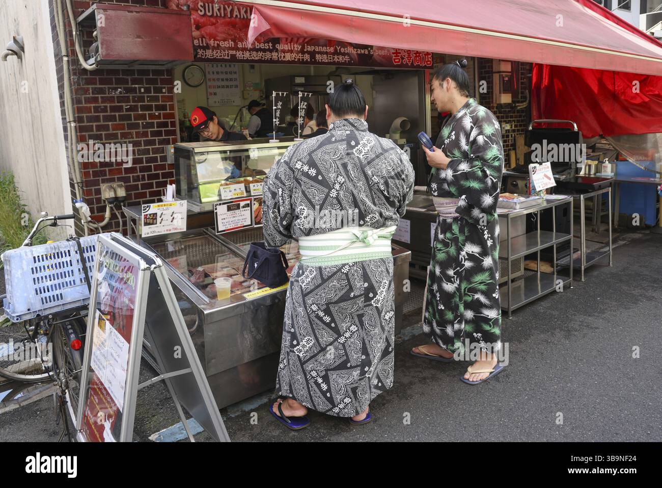 Due lottatori di Sumo in uno stand di cibo di strada nel mercato esterno di Tsukiji a Tokyo, Chuo City, Giappone, Asia Foto Stock