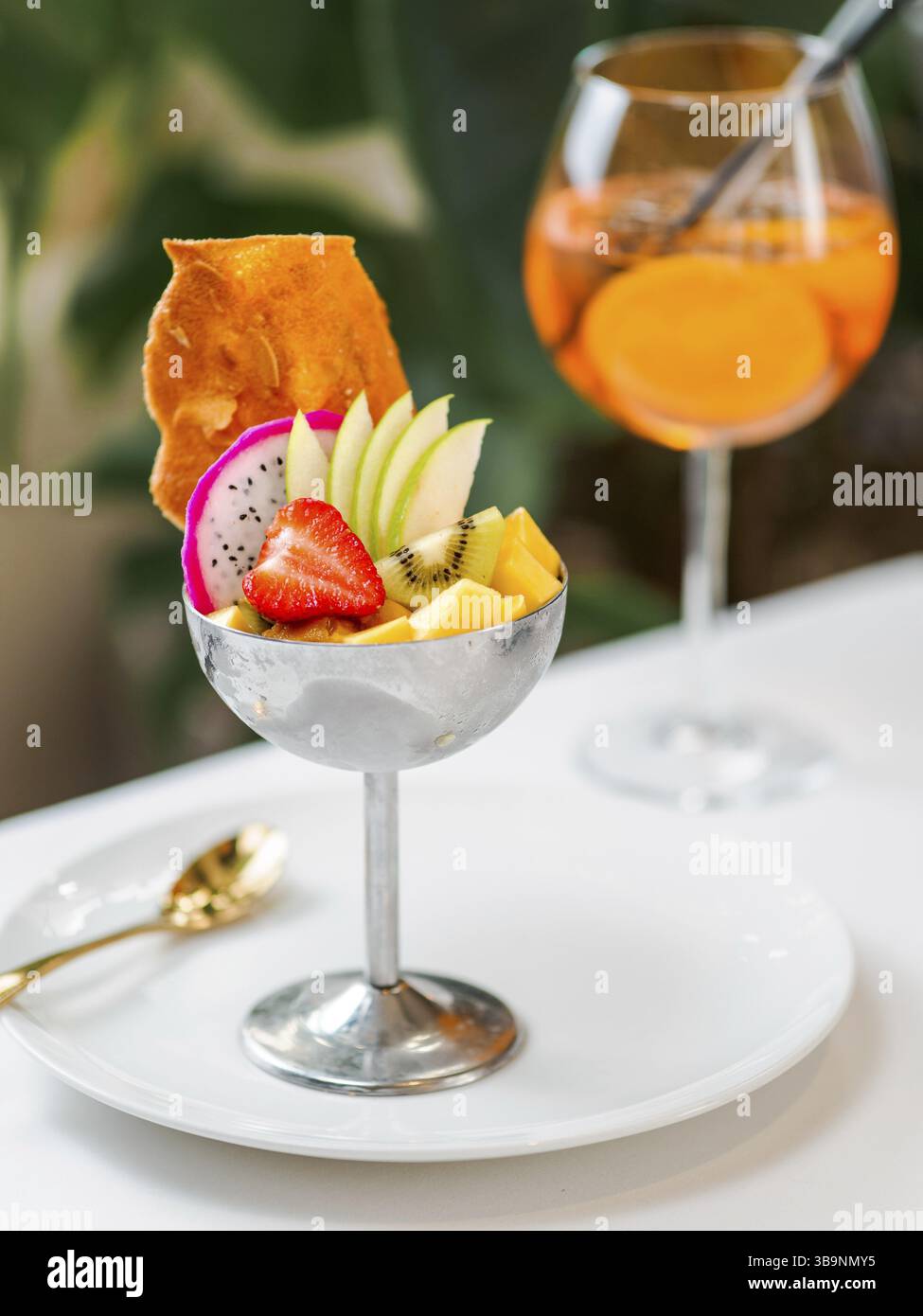 Sorbetto del Paradiso tropicale con pompelmo, mango, frutto della passione decorato con frutta fresca e croccanti biscotti di tuile. Gelato tropicale in sundae di metallo Foto Stock