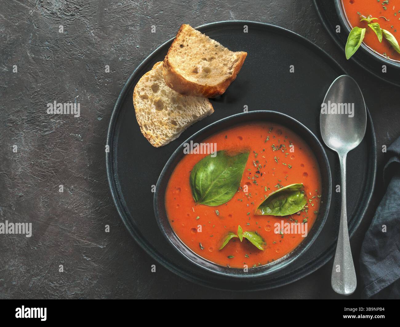 Zuppa di Gaspacho in ciotola nera. Zuppa fredda spagnola tradizionale gaspacho purea o gazpacho su sfondo scuro con spazio di copia per il testo. Vista dall'alto o appartamento la Foto Stock
