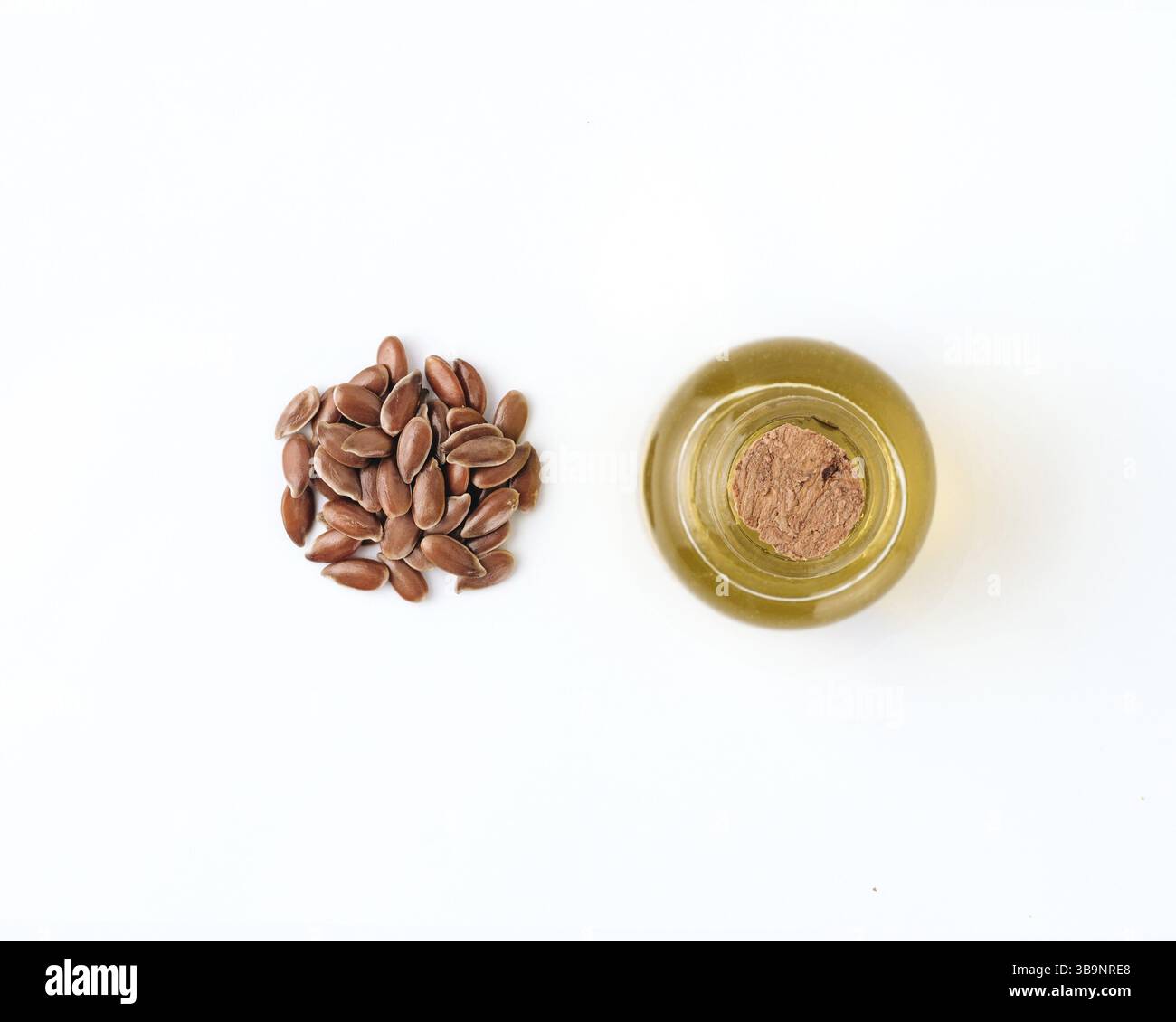 Semi di lino e olio grezzo di lino isolati su sfondo bianco. Cumulo di semi di lino e olio di semi di lino crudo in una piccola bottiglia di vetro isolata su bianco con clip Foto Stock