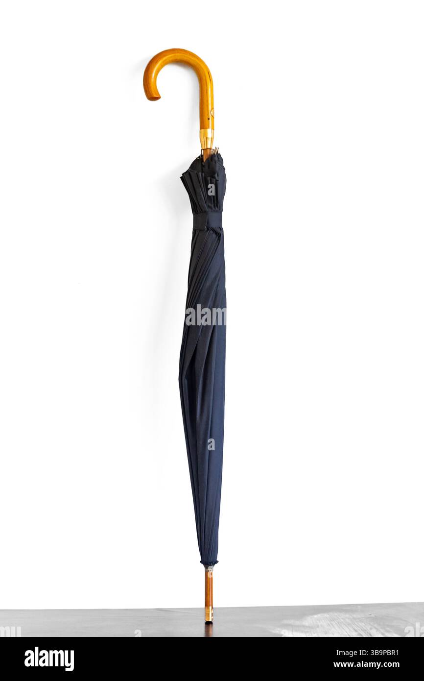 Tipico ombrello nero chiuso e isolato su sfondo bianco Foto Stock