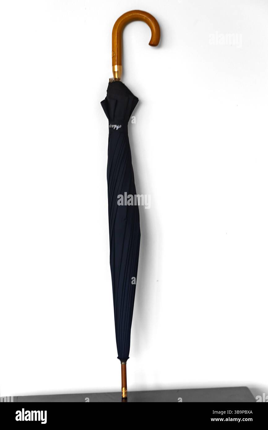 Tipico ombrello nero chiuso e isolato su sfondo bianco Foto Stock