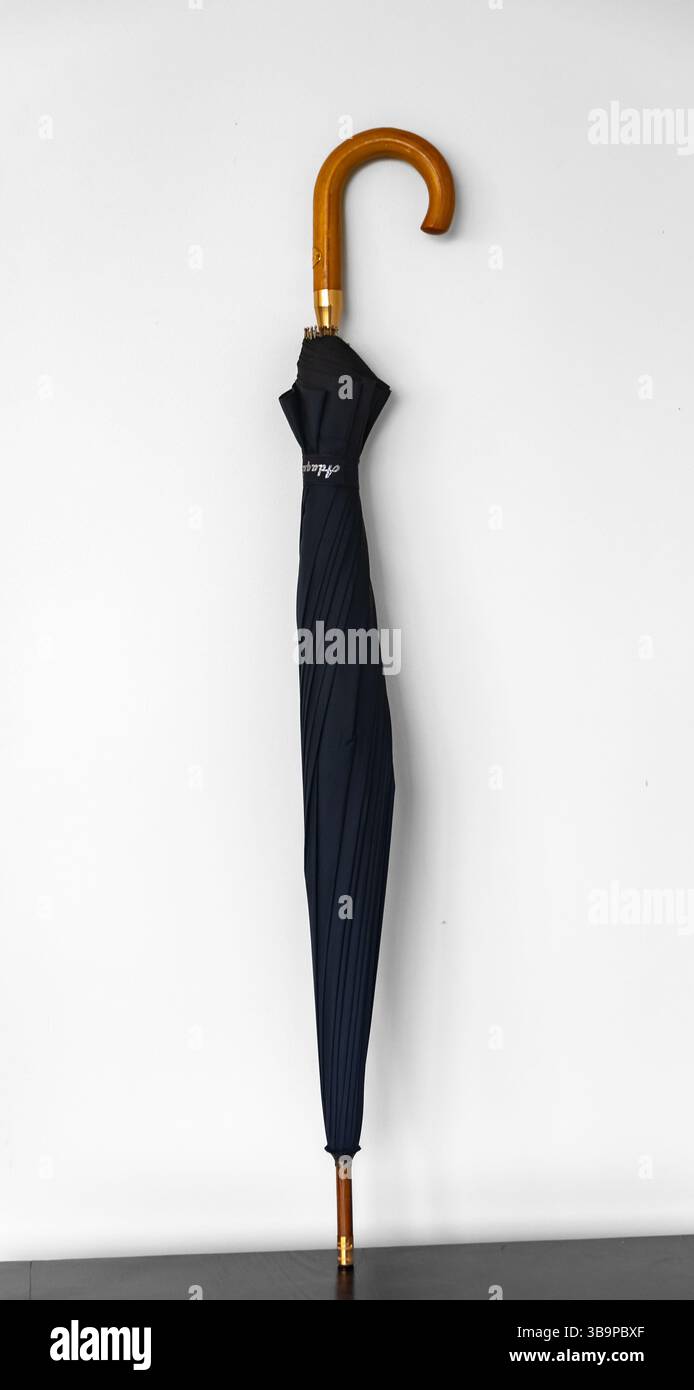 Tipico ombrello nero chiuso e isolato su sfondo bianco Foto Stock