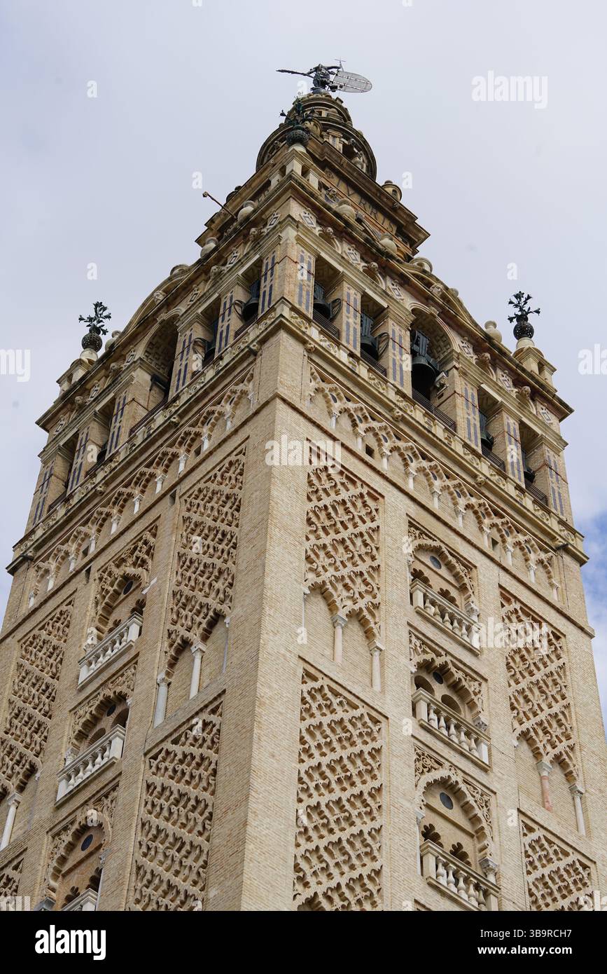 Vista verso l'alto della torre la Giralda presso la cattedrale di Siviglia, Spagna, che mostra la facciata decorata, gli archi e i dettagli architettonici storici. Siviglia, Spagna Foto Stock