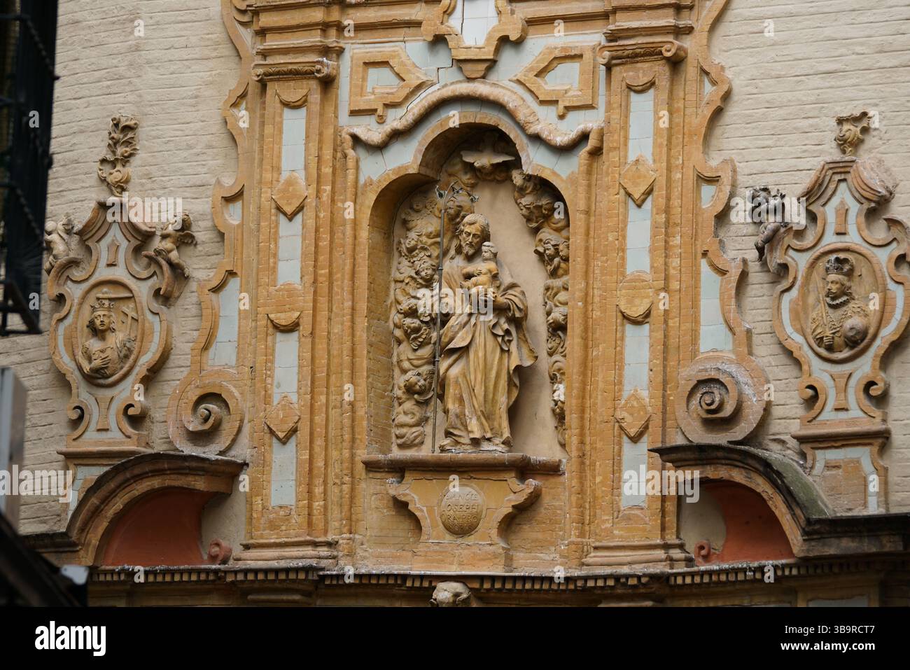 Facciata religiosa barocca ornata con una nicchia di statue, decorazioni scolpite e iconografia sacra a Siviglia, Spagna. Siviglia, Spagna Foto Stock