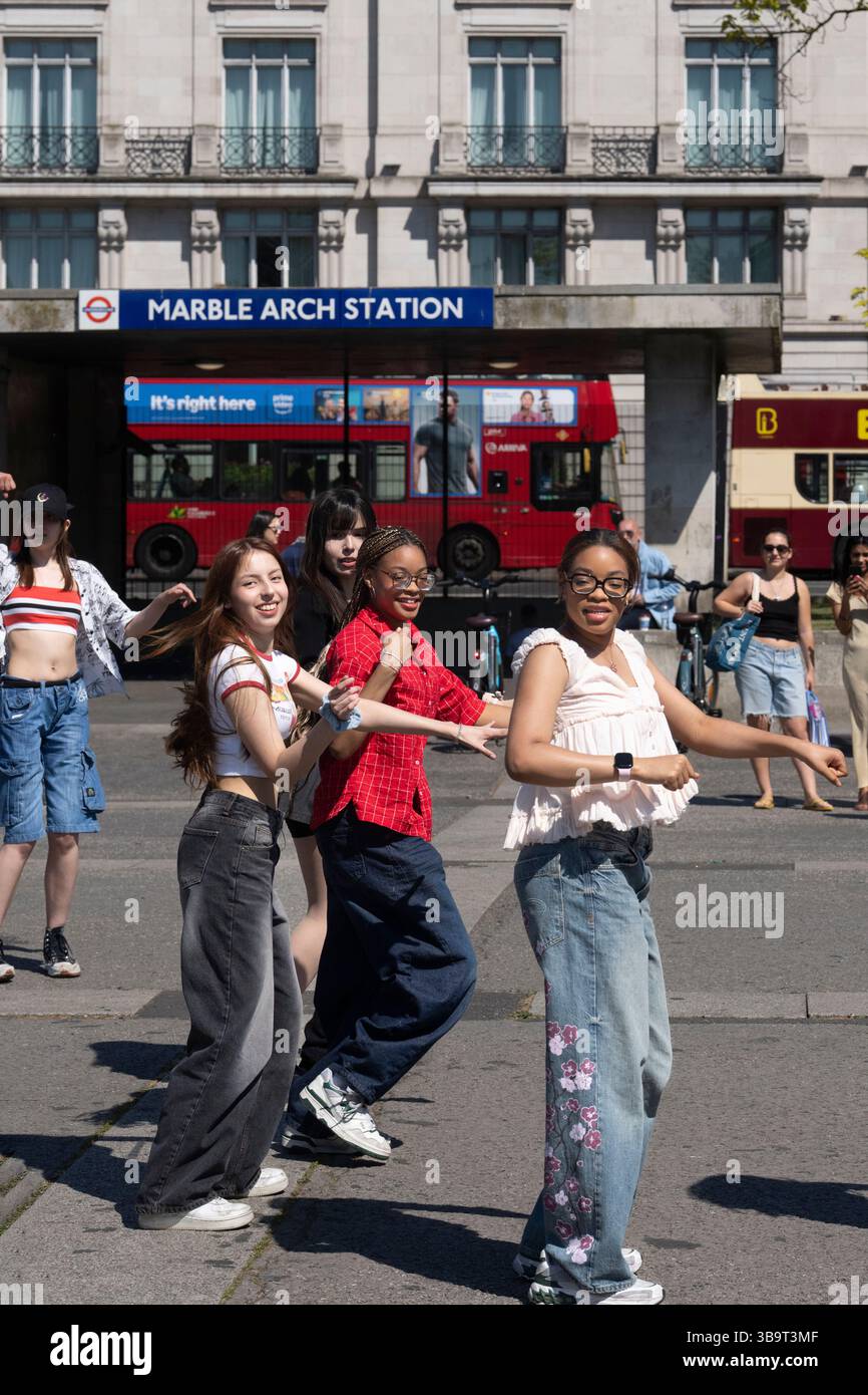 Un gruppo di giovani danza di fronte alla stazione Marble Arch di Londra, probabilmente filma contenuti per i social media. Foto Stock