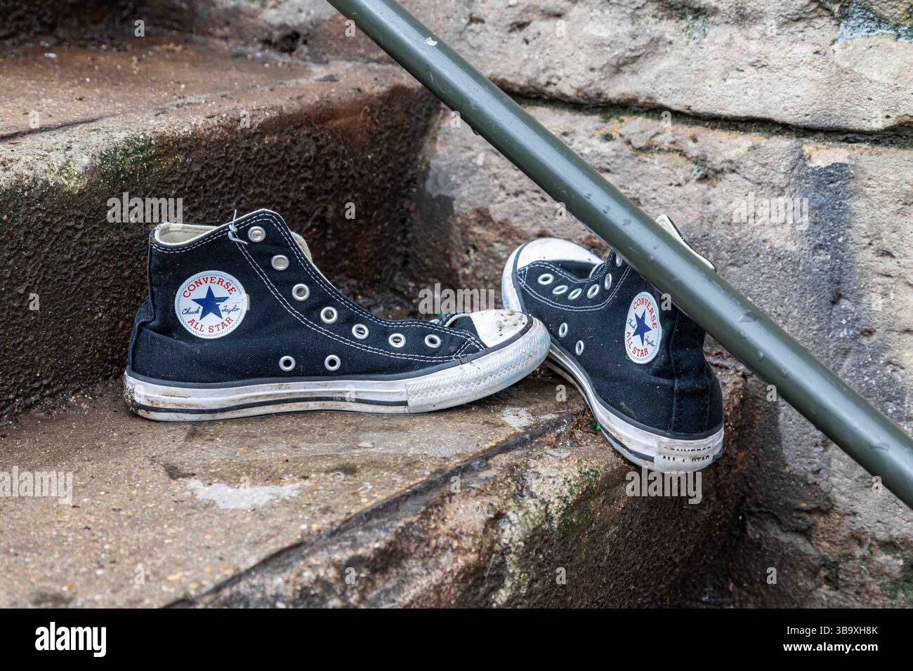 Scarpe da ginnastica abbandonate Converse All Stars su scale di cemento nel quartiere Canal Saint-Martin di Parigi, Francia Foto Stock