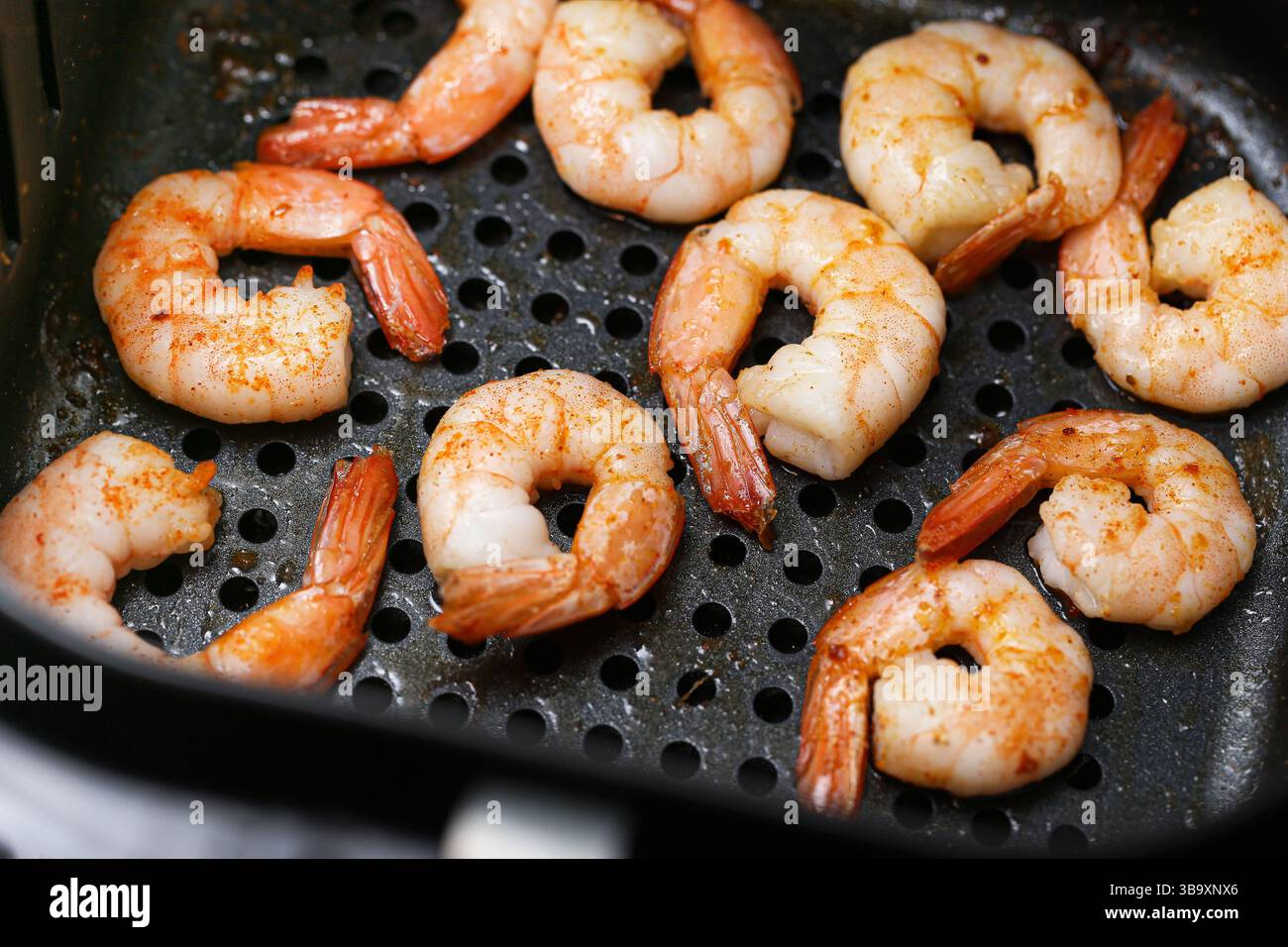 Gamberi grigliati nella friggitrice ad aria. Primo piano di un gustoso pasto a base di pesce. Succosi gamberi con spezie. Pranzo o cena salutari. Cucina in stile barbecue. Foto Stock