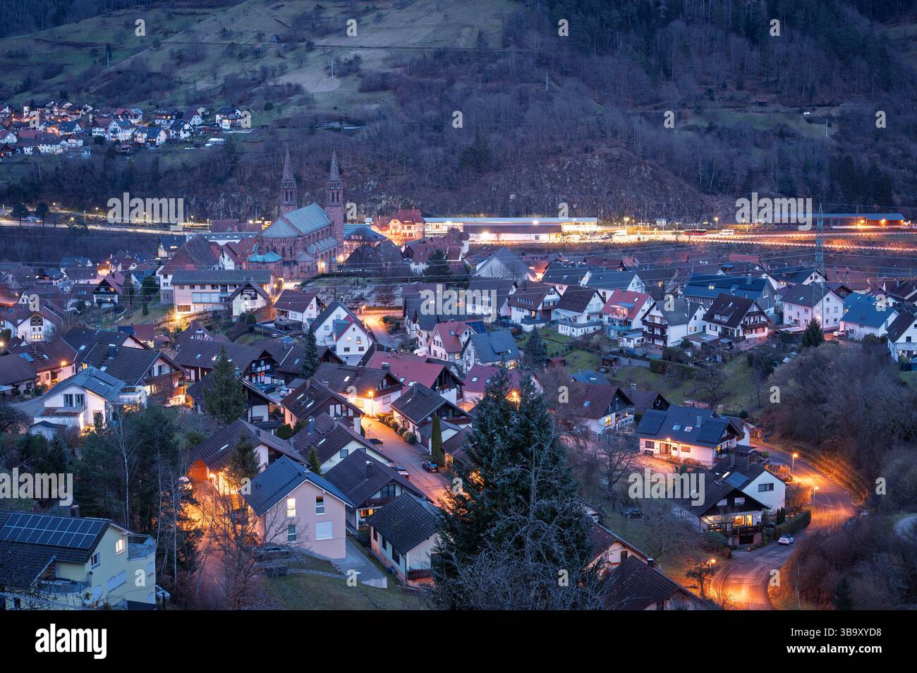 La serata si svolge a Forbach, in Germania, mentre le luci del villaggio brillano tra le case annidate nel pittoresco paesaggio della Foresta Nera. Foto Stock