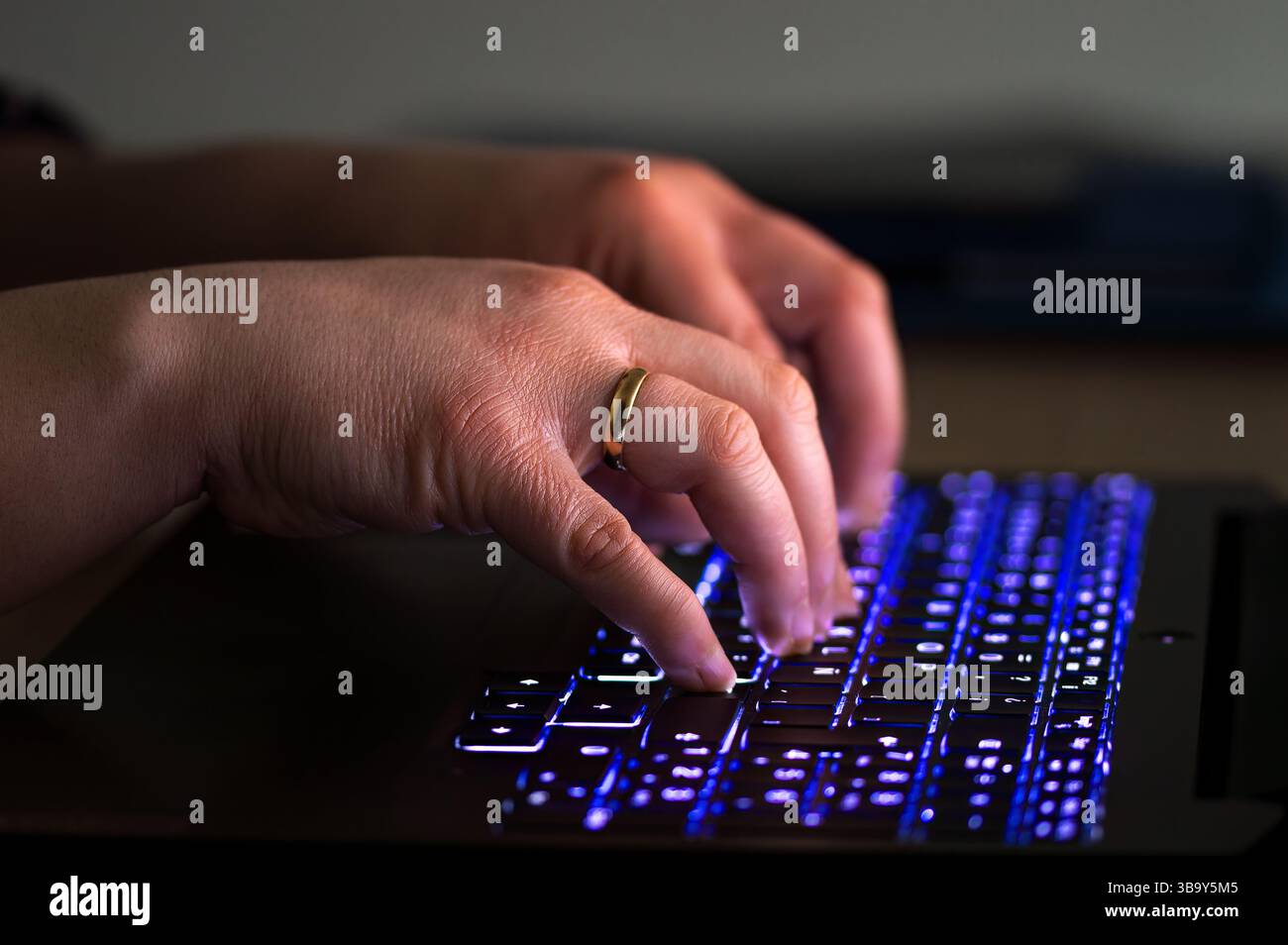 Primo piano delle mani di una donna con la retroilluminazione di una tastiera per notebook e di una tastiera retroilluminata Foto Stock
