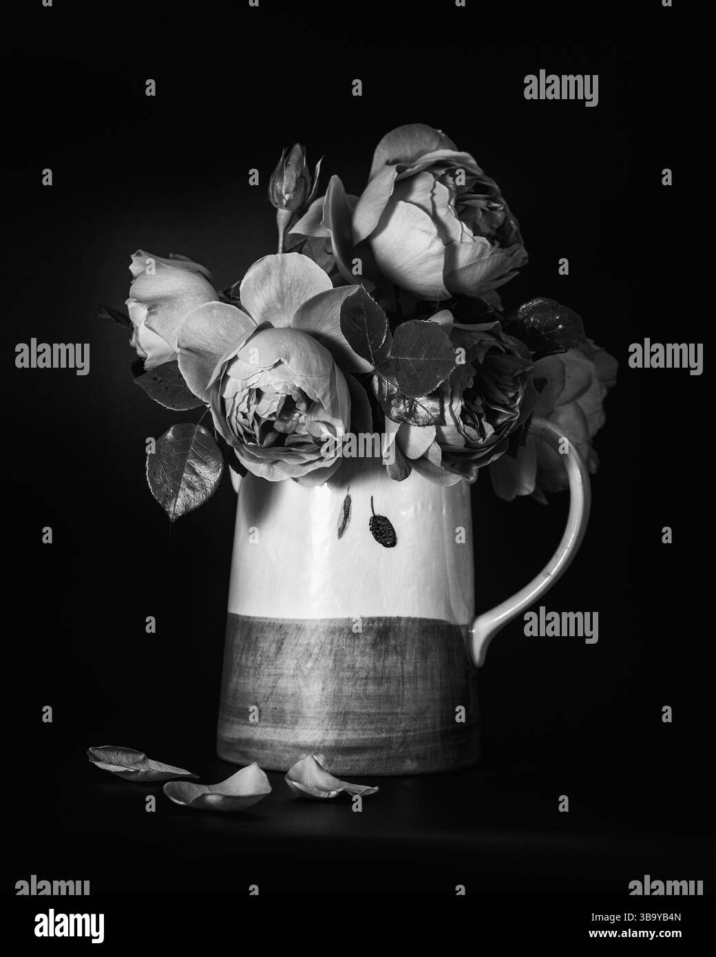 Immagine in bianco e nero di una caraffa con motivo di oliva piena di rose in fiore Foto Stock