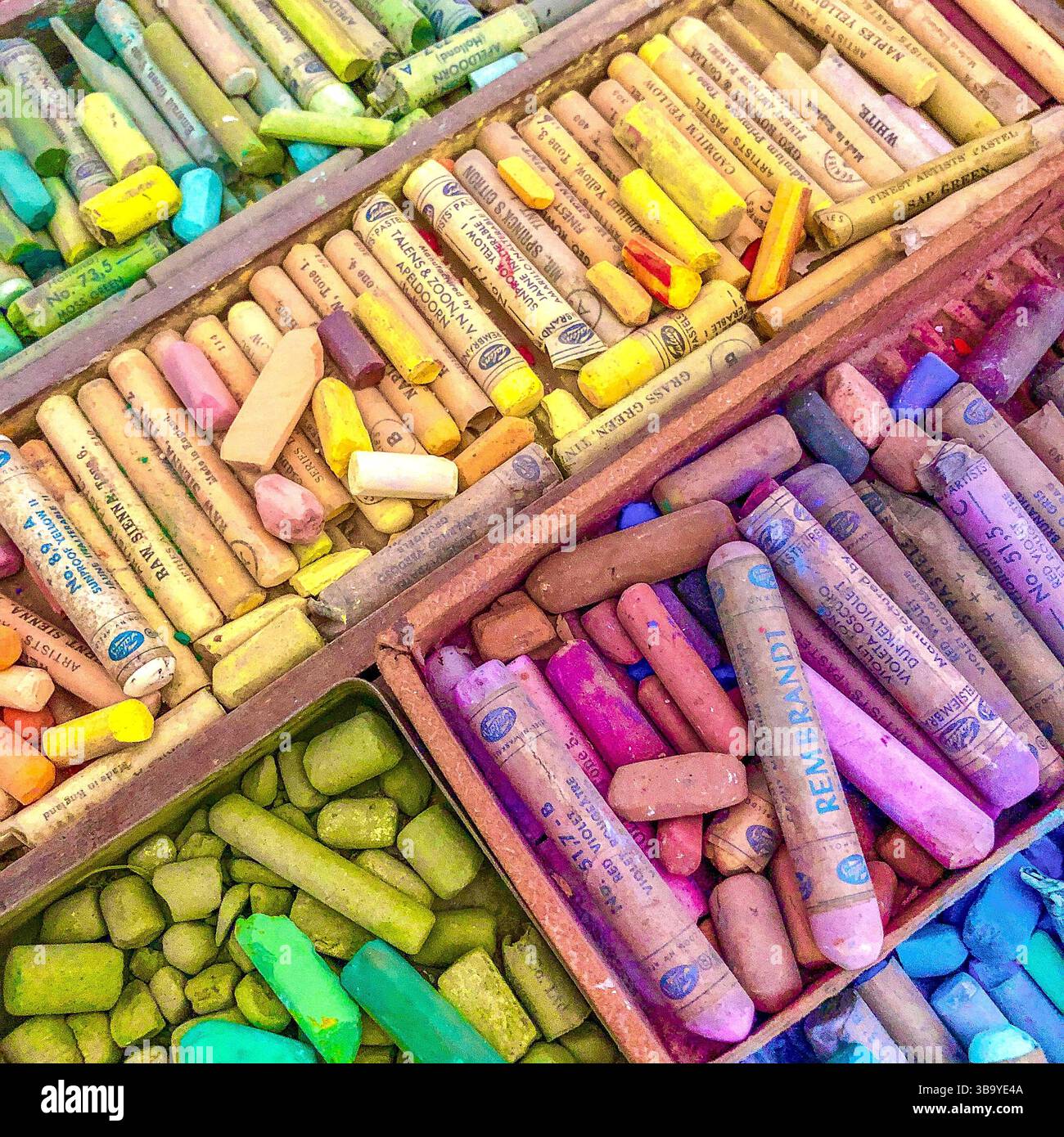 Colori assortiti e sfumature di giallo, verde, blu e viola dei pastelli pastello dell'artista. Foto Stock