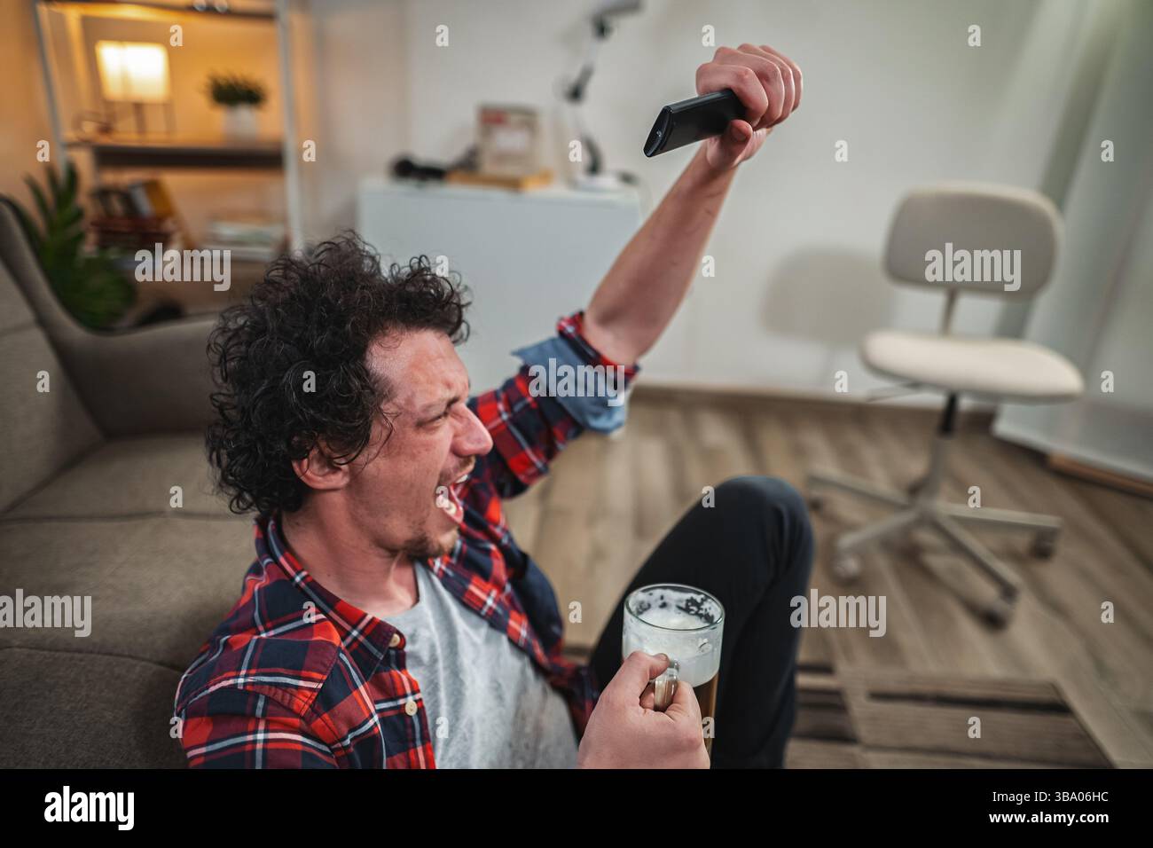 Tifosi entusiasti dello sport mentre guardano la tv e bevono birra Foto Stock