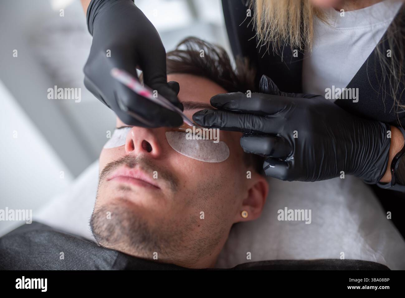 Un giovane in un salone di bellezza che si prende cura delle ciglia. Foto Stock
