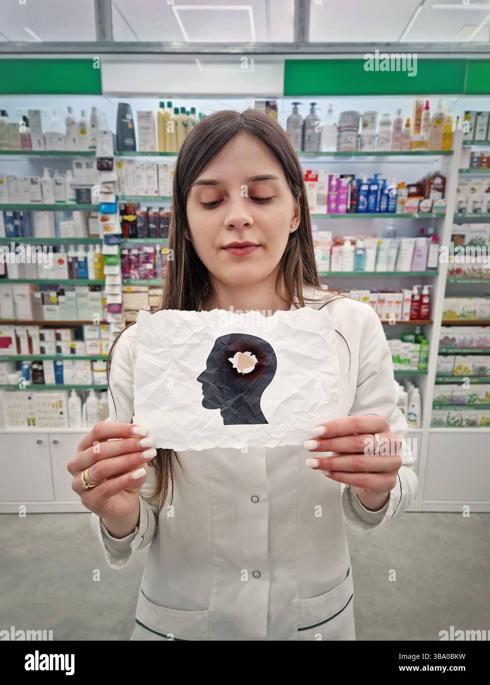 Donna lavoratrice medica che tiene in mano una carta sfregata con una silhouette esplosa della testa. Salute mentale e concetto di perdita di memoria umana. Noi fisici ed emotivi - Immagine stock catturata con smartphone
