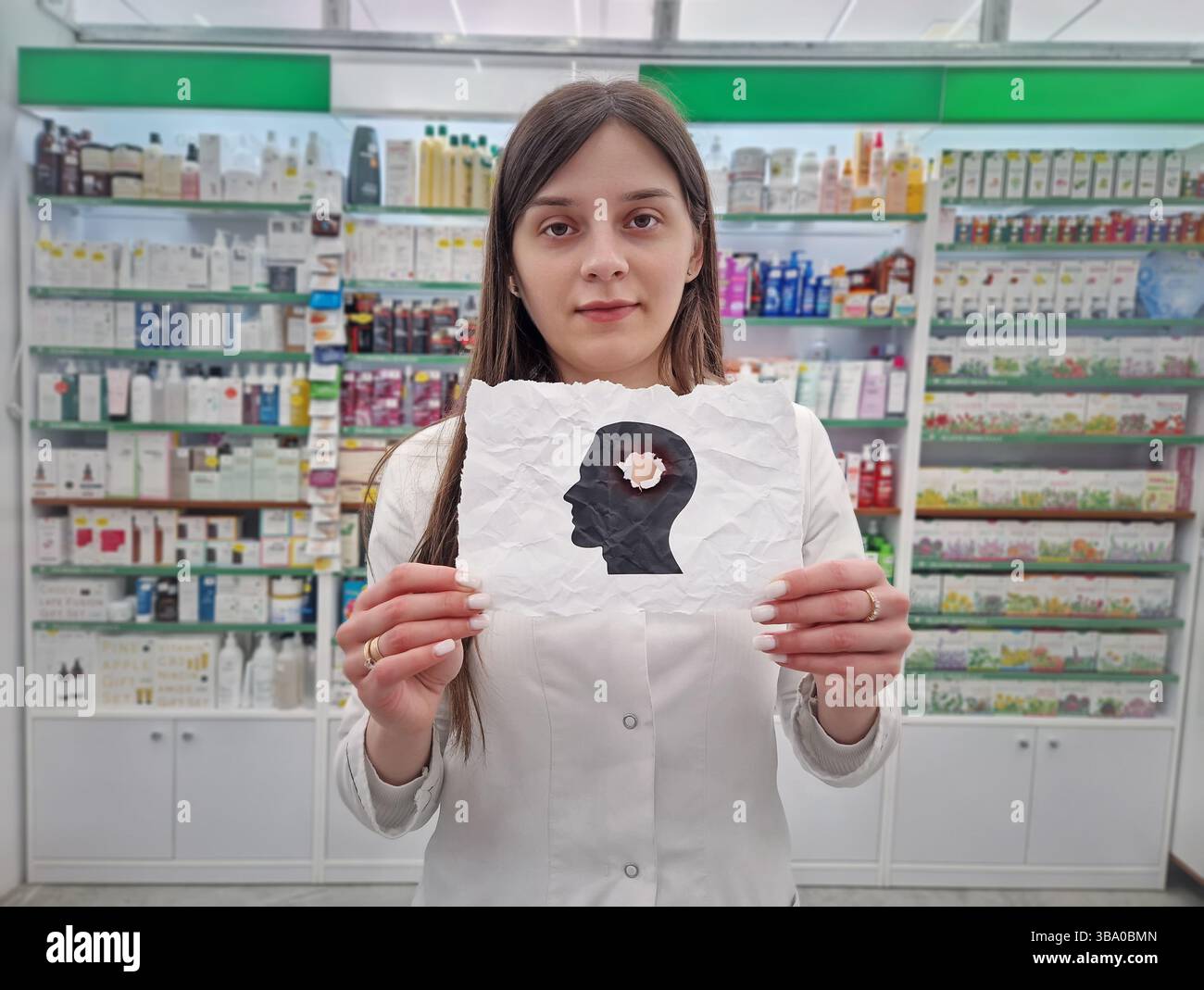 Donna lavoratrice medica che tiene in mano una carta sfregata con una silhouette esplosa della testa. Salute mentale e concetto di perdita di memoria umana. Noi fisici ed emotivi Foto Stock