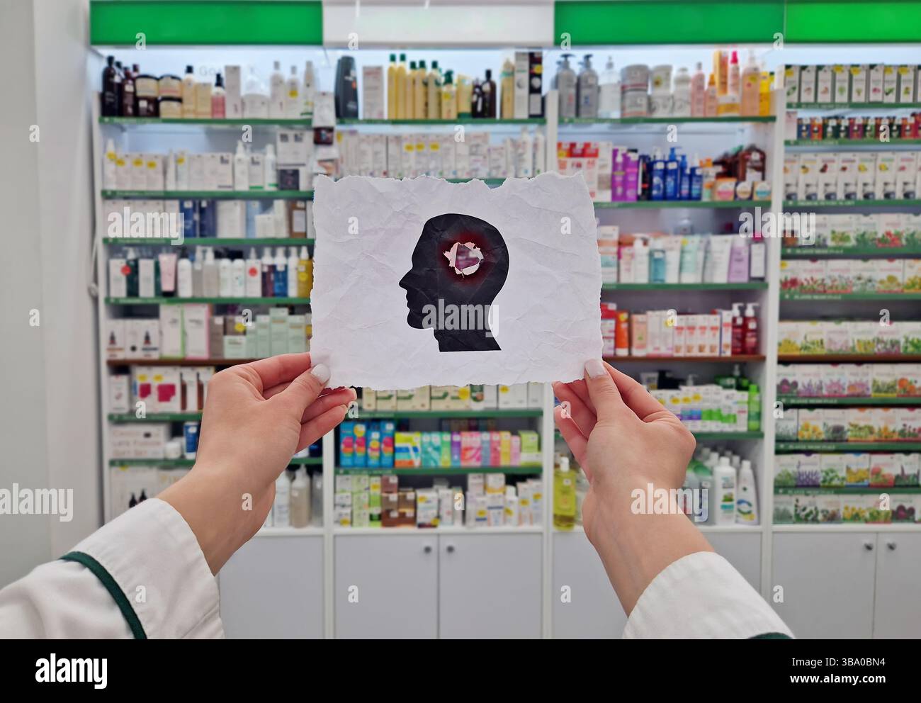 Mani del farmacista che tengono in mano una carta sgualcita con una silhouette esplosa della testa. Salute mentale e concetto di perdita di memoria umana. Benessere fisico ed emotivo Foto Stock
