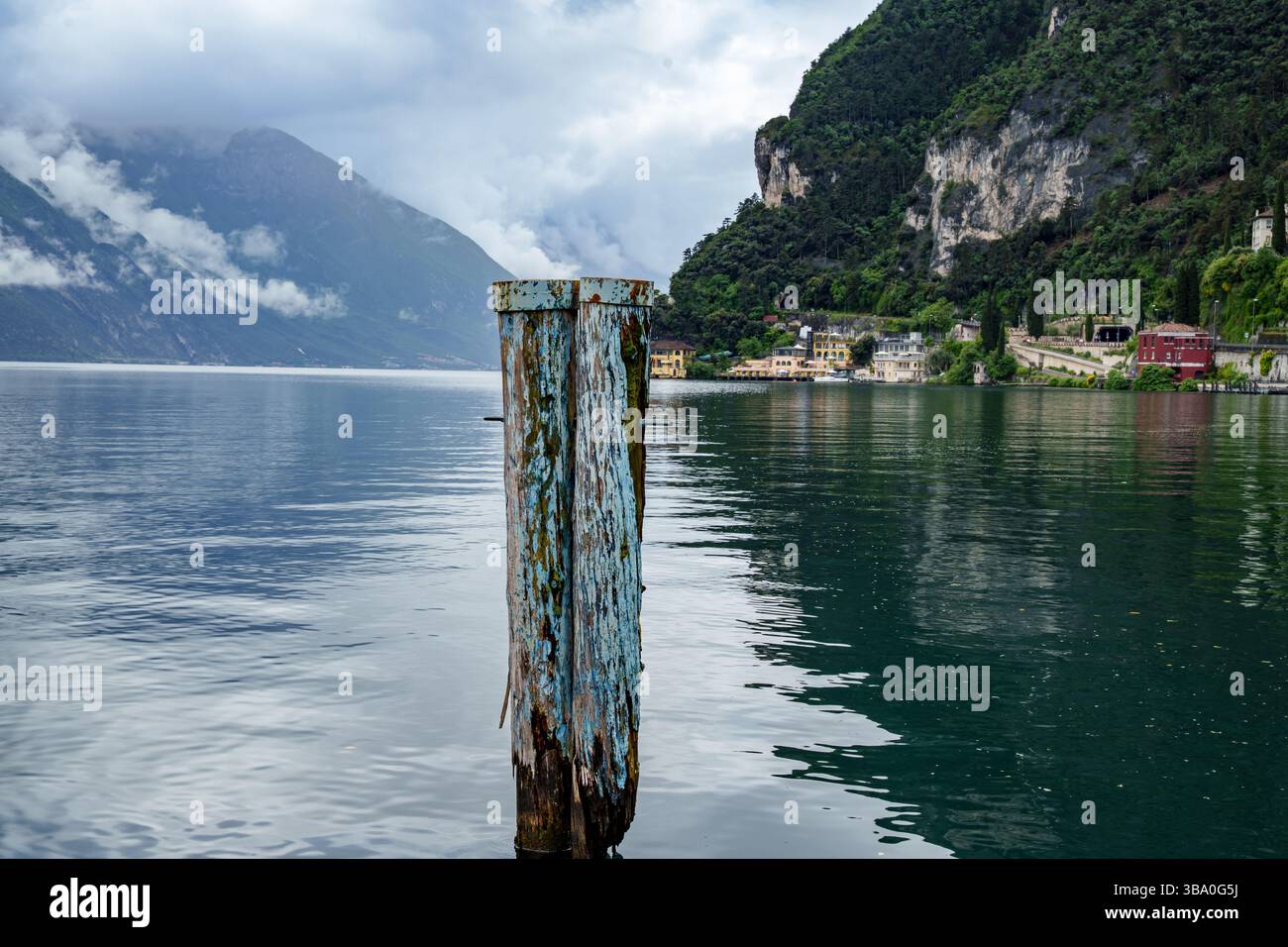 Due pali di legno blu e intemperie per l'ancoraggio delle navi sul Lago di Garda, Italia. Cielo nuvoloso con un'atmosfera di tempesta Foto Stock