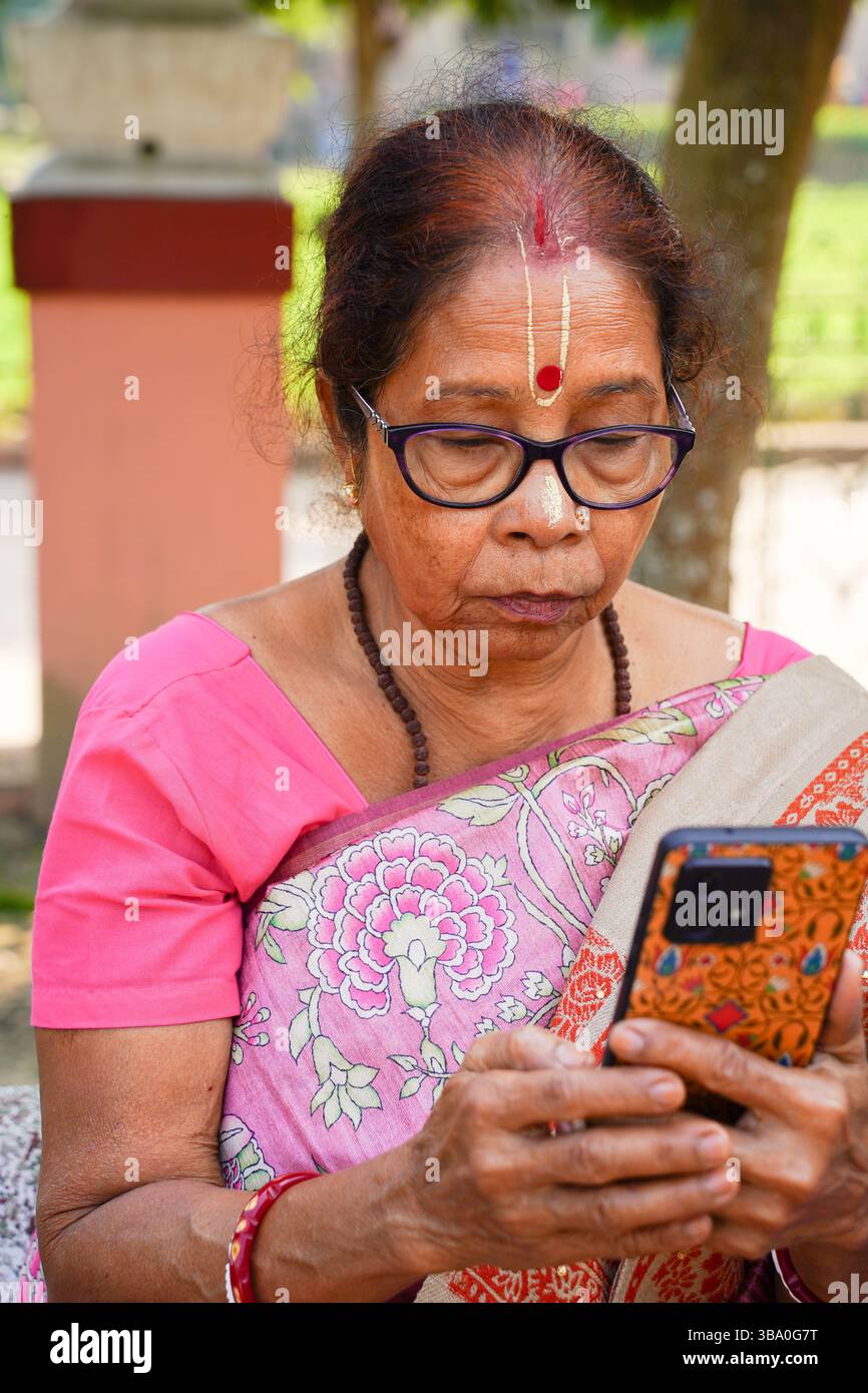 Primo piano di una donna di 73 anni con un tilak spirituale, avvolto in uno splendido scialle, seduto pacificamente su una barca sul fiume Bhagirathi in inverno. Foto Stock
