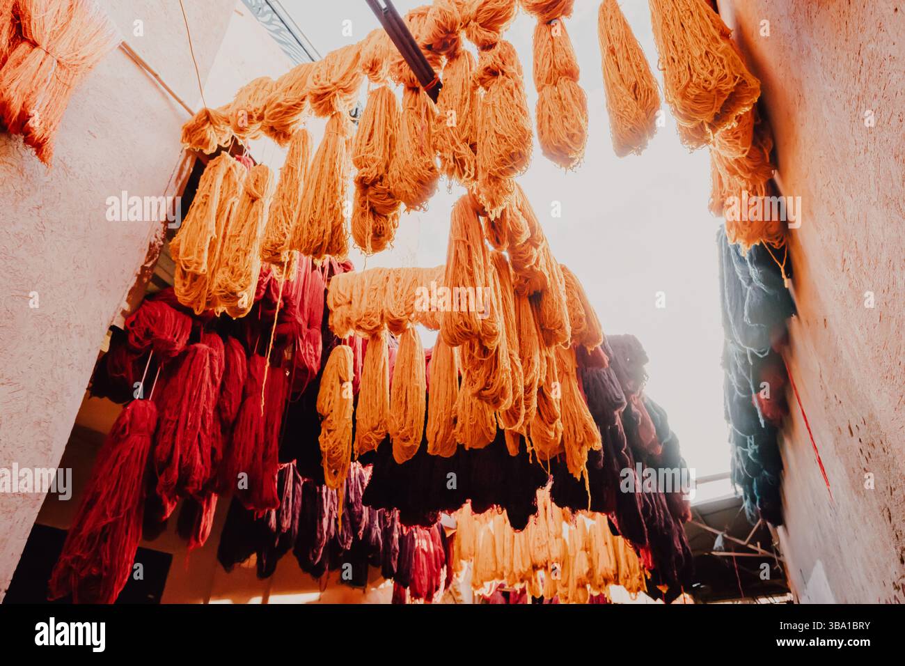 Filati di lana colorati appesi e asciugati in un tradizionale laboratorio di conceria marocchina a Marrakech Foto Stock