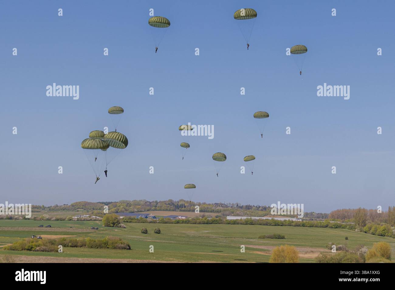Paracadutisti tedeschi durante un'esercitazione NATO in Germania, completamente equipaggiati, che scendono dagli aerei e si coordinano a terra in un addestramento forestale Foto Stock