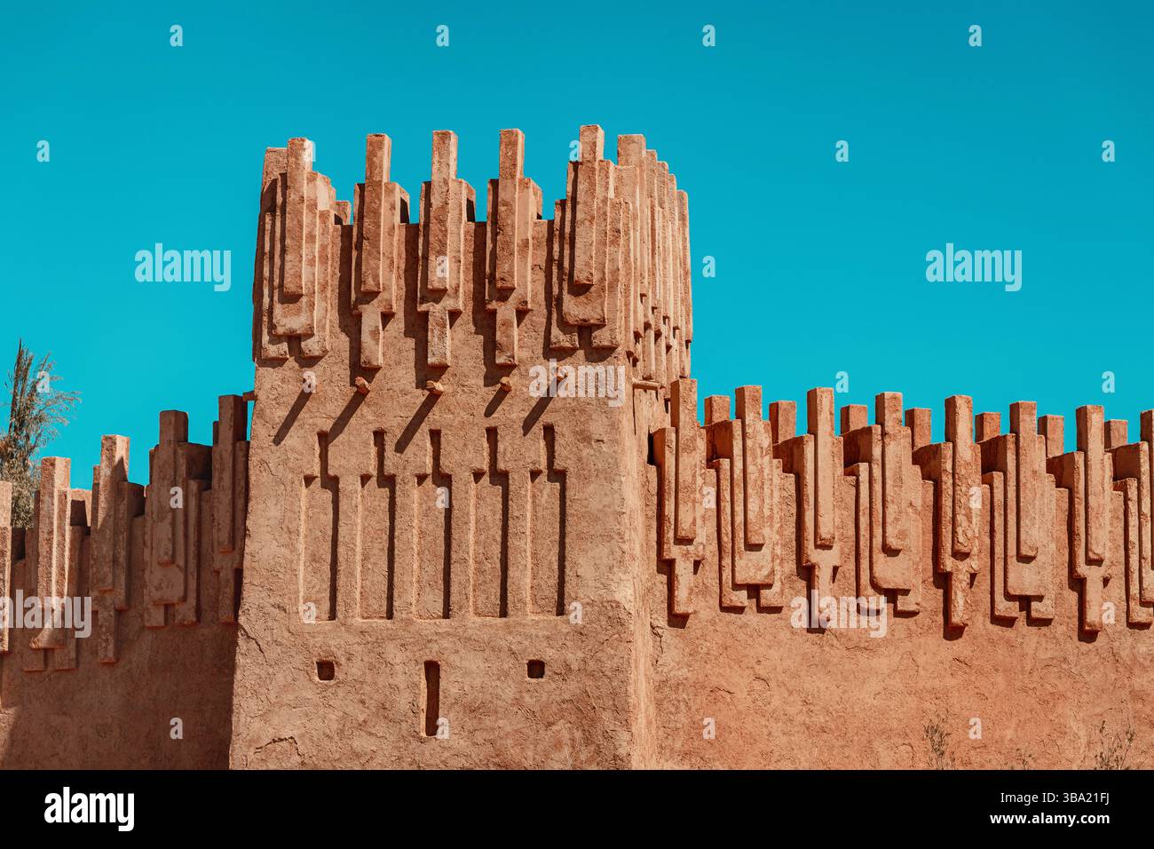 Mura e torri ornate di Ait Benhaddou, uno storico ksar, che mostra la tradizionale architettura marocchina in terra battuta contro un vibrante cielo blu Foto Stock