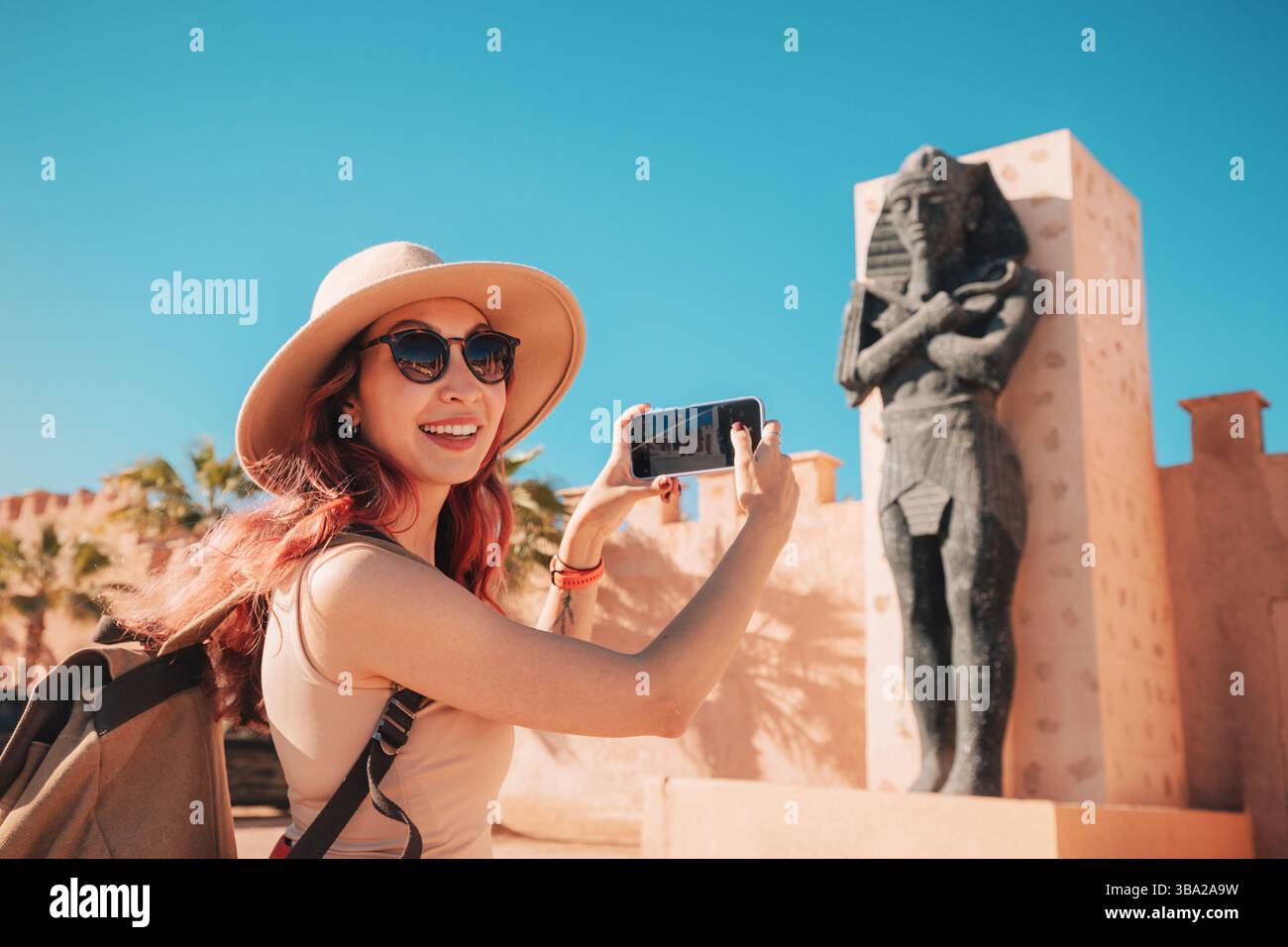 7 marzo 2025, Ouarzazate, Marocco: Turista sorridente che scatta una foto con una statua del faraone agli Atlas Studios Foto Stock