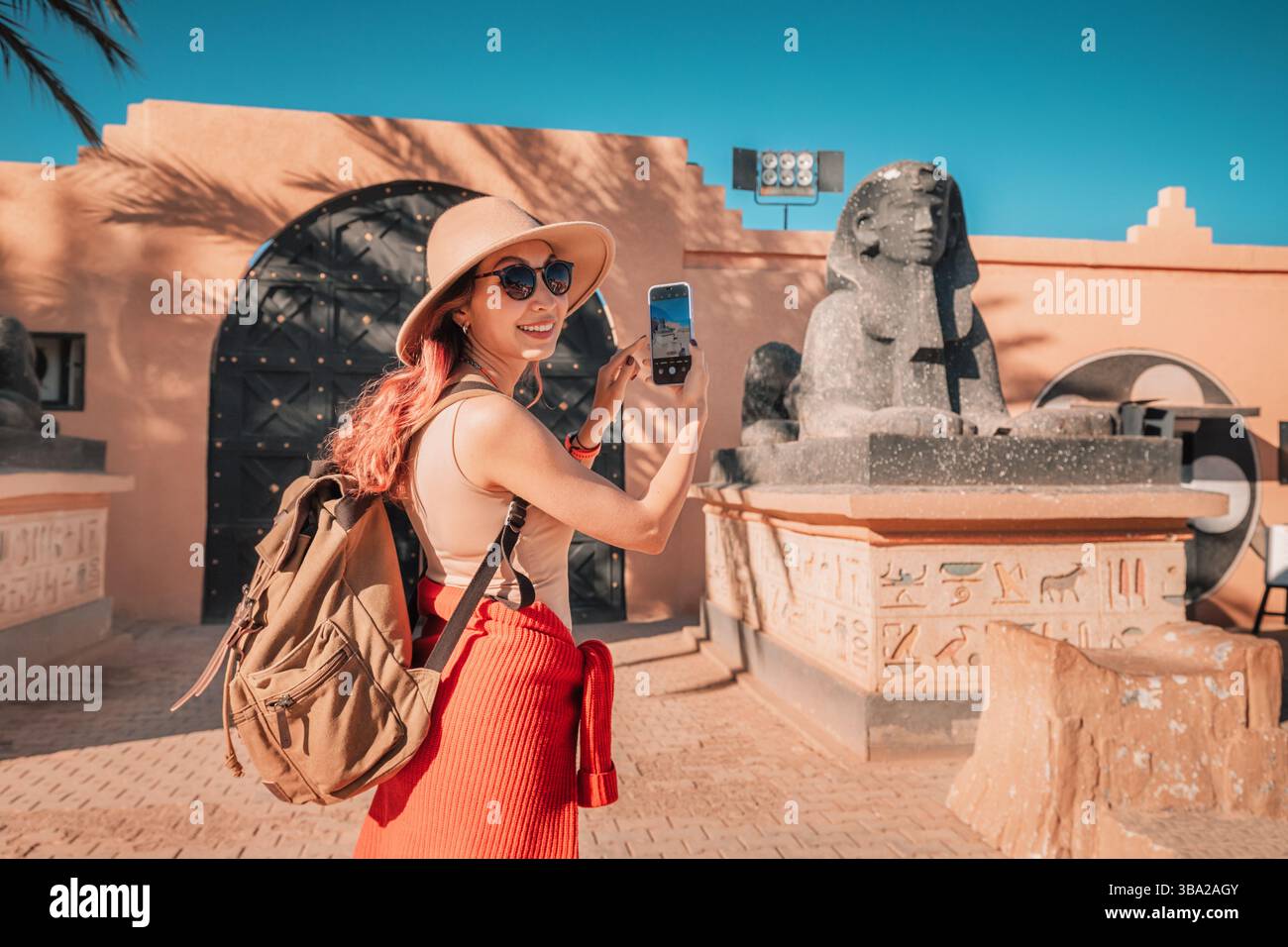 7 marzo 2025, Ouarzazate, Marocco: Turista sorridente che scatta una foto con una statua del faraone agli Atlas Studios Foto Stock