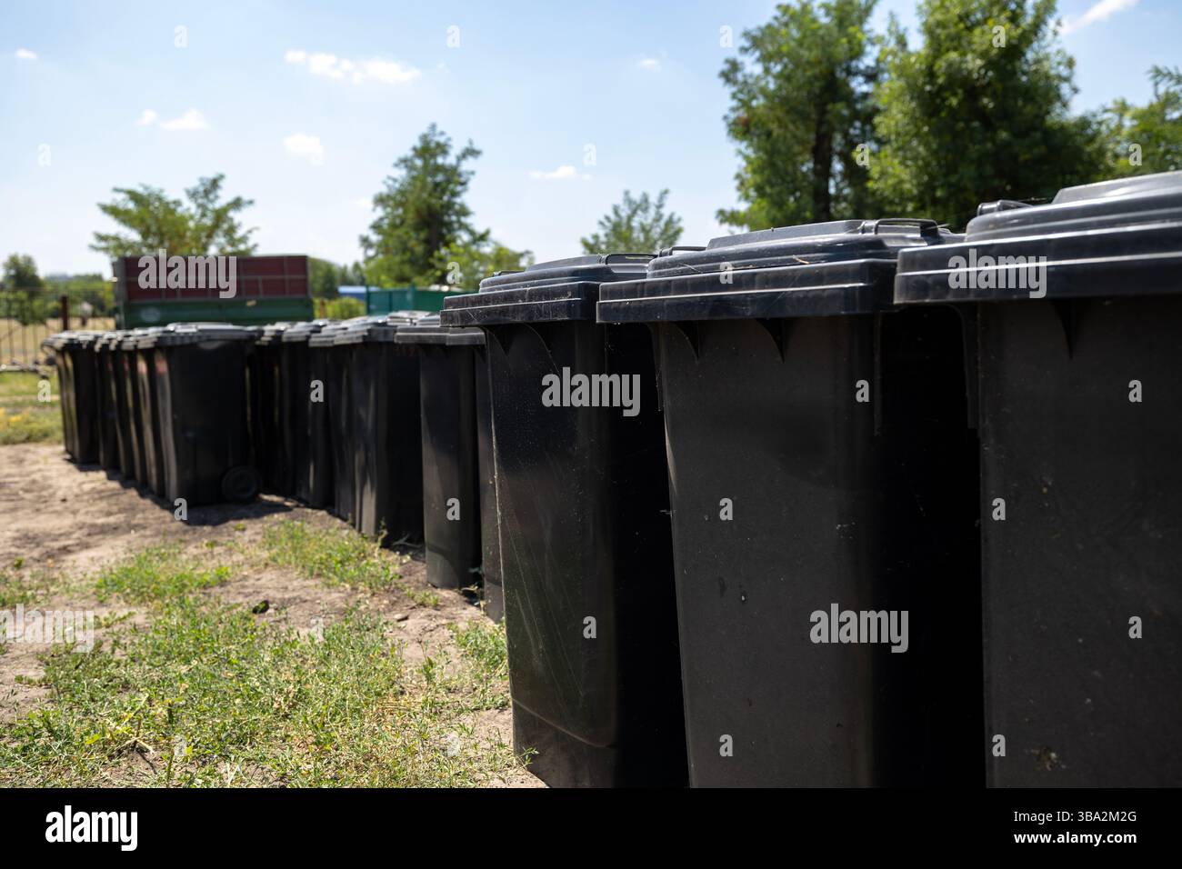 Un gran numero di contenitori per rifiuti neri disposti in file presso un impianto di stoccaggio per un servizio di rimozione dei rifiuti. Si sono organizzati in modo ordinato e pronti per il quartiere Foto Stock
