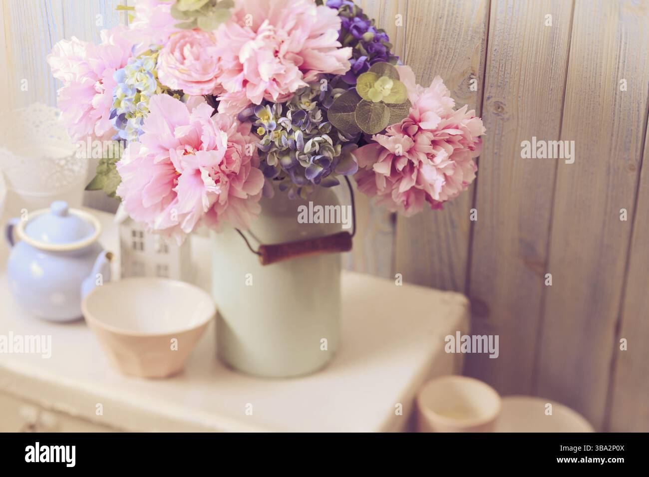 Fiori in una lattina vintage blu su borsa retrò bianco e terracotta da cucina Foto Stock
