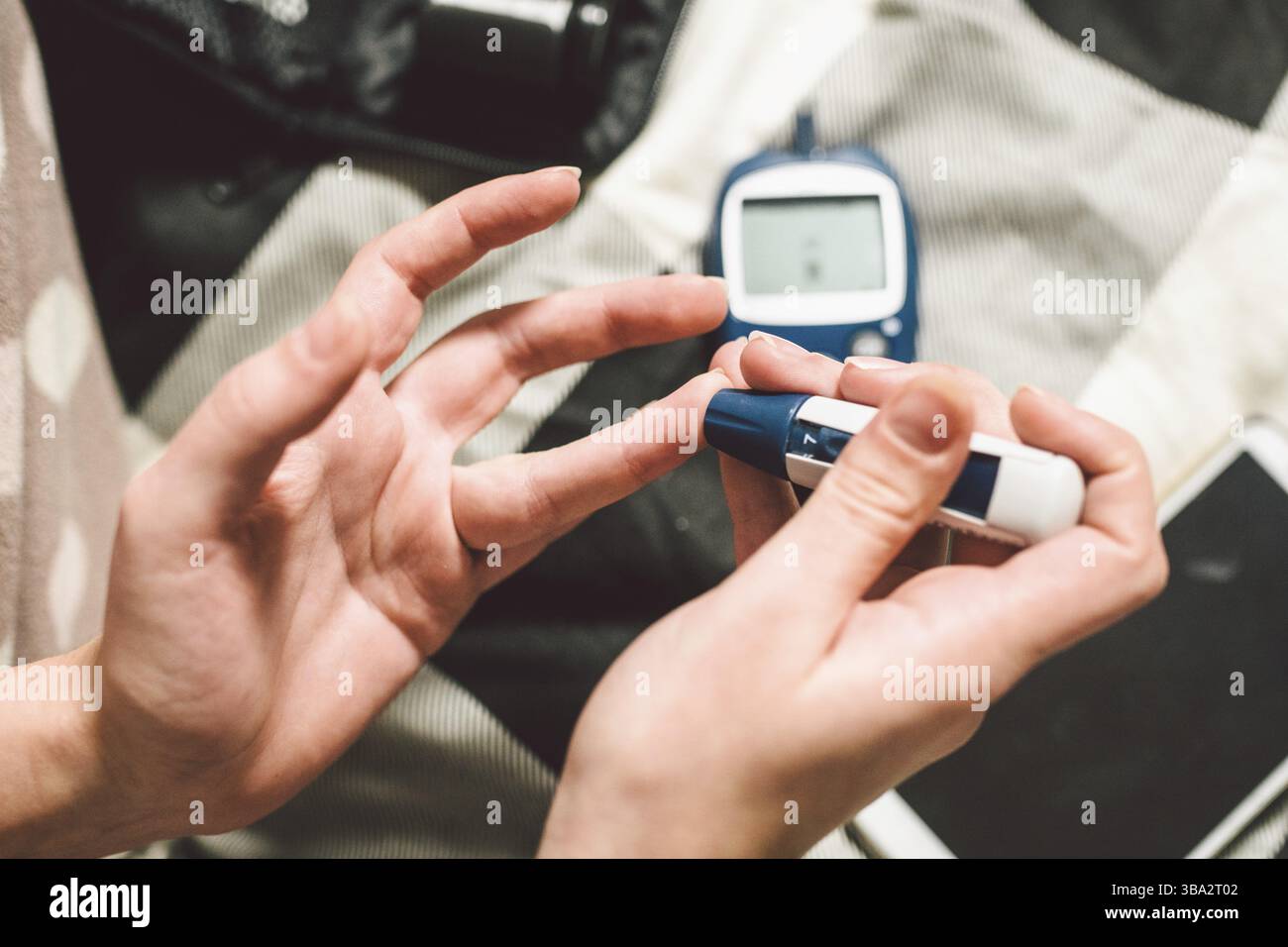 Tema del diabete. Un close-up macro-piano. Mani di una giovane donna caucasica a casa in camera da letto sul letto. Esso utilizza la tecnologia di un strumento per Foto Stock