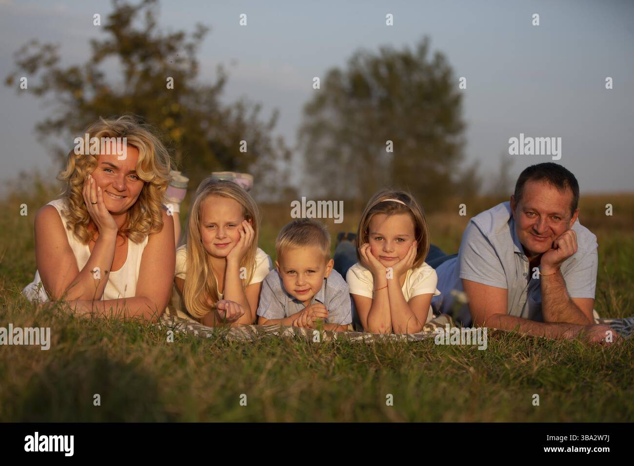Famiglia felice: Madre, padre, figli, figlio e figlie in natura. Una bella famiglia giace sull'erba del parco Foto Stock