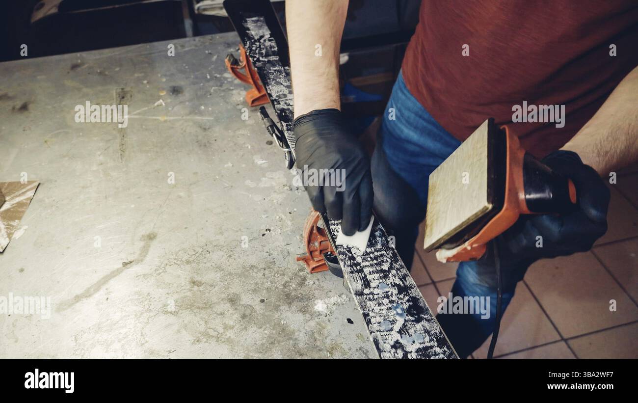 Applicazione di cera calda a base di sci con ferro. Applicazione di cera di sci di fondo sci. Base di sci tuning. Sci wax ferro e barre di cera. Il servizio sci e riparazione. repairman in Foto Stock