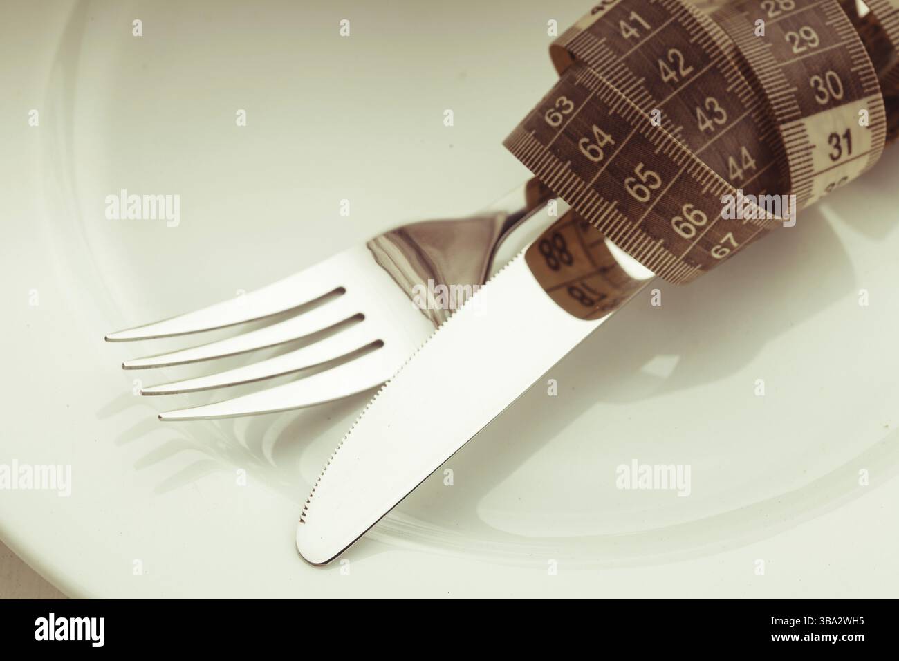 Forchetta e coltello con misuratore sulla piastra bianca vuota, concetto di dieta Foto Stock