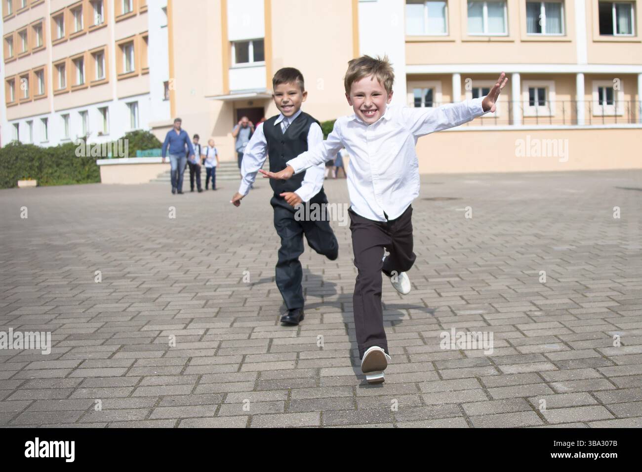 Ragazzi gli scolari corrono lungo la strada. Bambini gioiosi sullo sfondo della scuola.il ragazzo sta correndo.fine dell'anno scolastico. Inizio a. Foto Stock