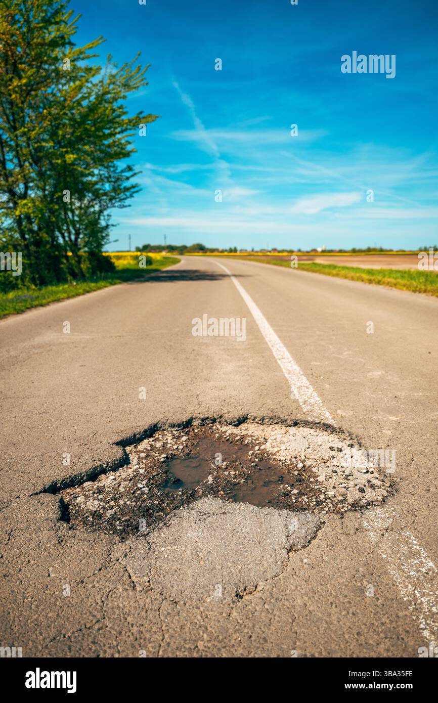 Grande foro su fondo stradale asfaltato, buco in una strada di campagna, attenzione selettiva Foto Stock