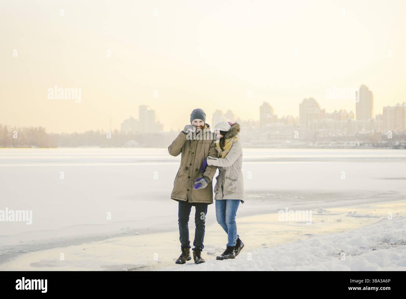 Vacanze natalizie a tema Capodanno invernale. Giovane elegante coppia caucasica amorevole eteresessuale che cammina sulla riva di un lago ghiacciato. Data. San Valentino D. Foto Stock