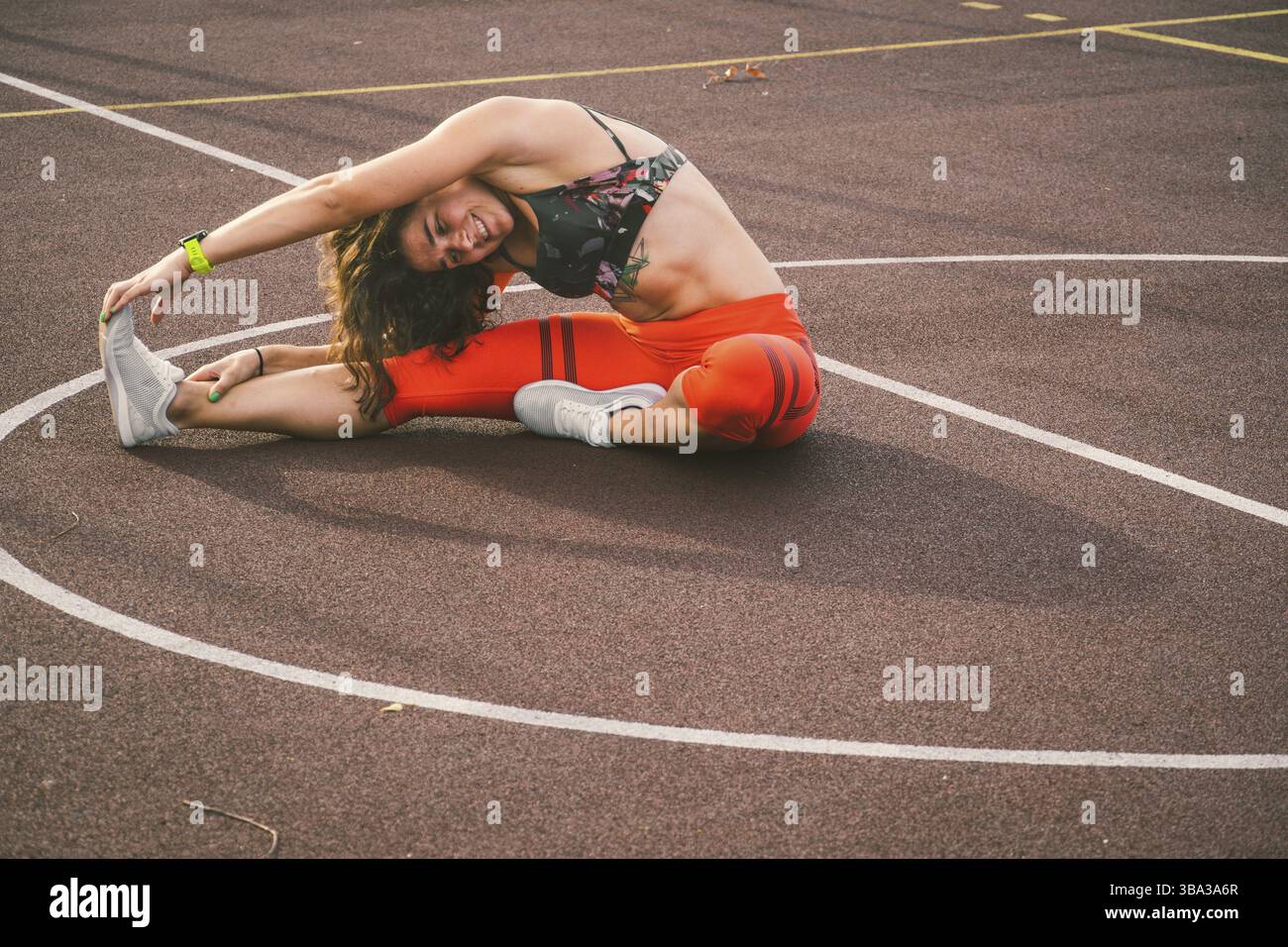 Atleta donna che allunga le gambe sullo stadio. Runner femminile che si allunga prima dell'allenamento. Ritratto dello stile di vita di una ragazza atletica che si sta riscaldando e allenando Foto Stock