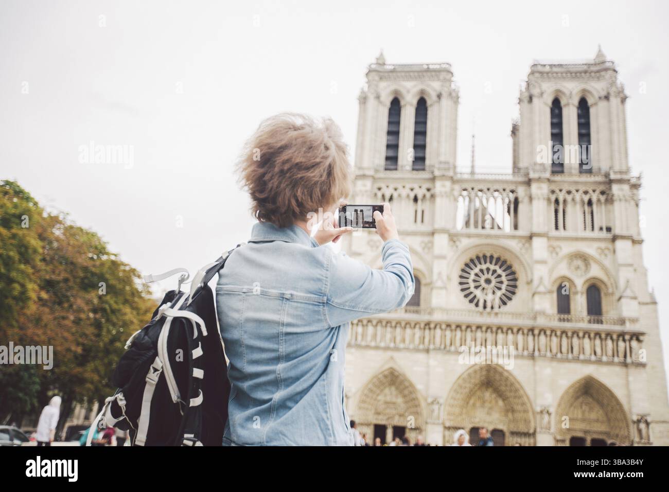Turista a Parigi facendo simpatico selfie vicino alla Cattedrale di Notre Dame. Bella giovane donna turistica caucasica con zaino a Parigi facendo divertente selfie han Foto Stock