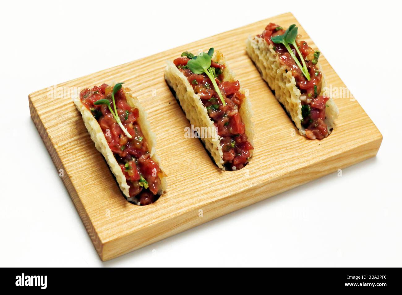 tartare di bistecca di manzo in conchiglie di parmigiano su una tavola di legno con sfondo bianco Foto Stock