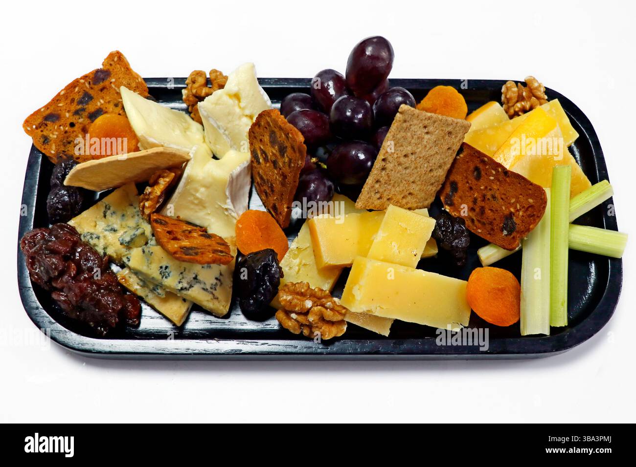 selezione di formaggi assortiti con frutta chutney, noci e cracker in un tagliere di legno Foto Stock