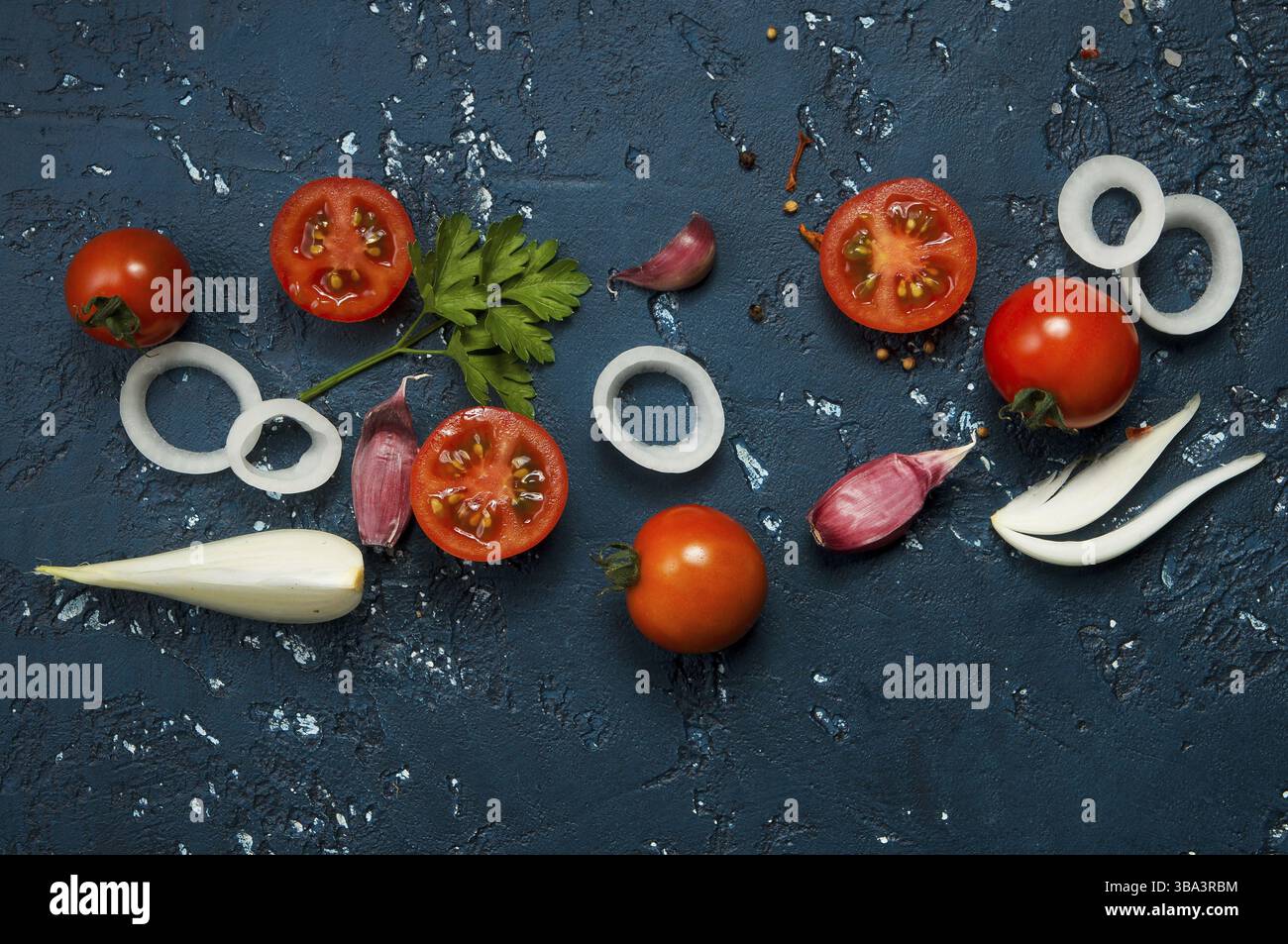 Sfondo di verdure. Verdure fresche (aglio, pomodori, cipolle) su una superficie scura in rilievo. Vista dall'alto. Copia spazio Foto Stock