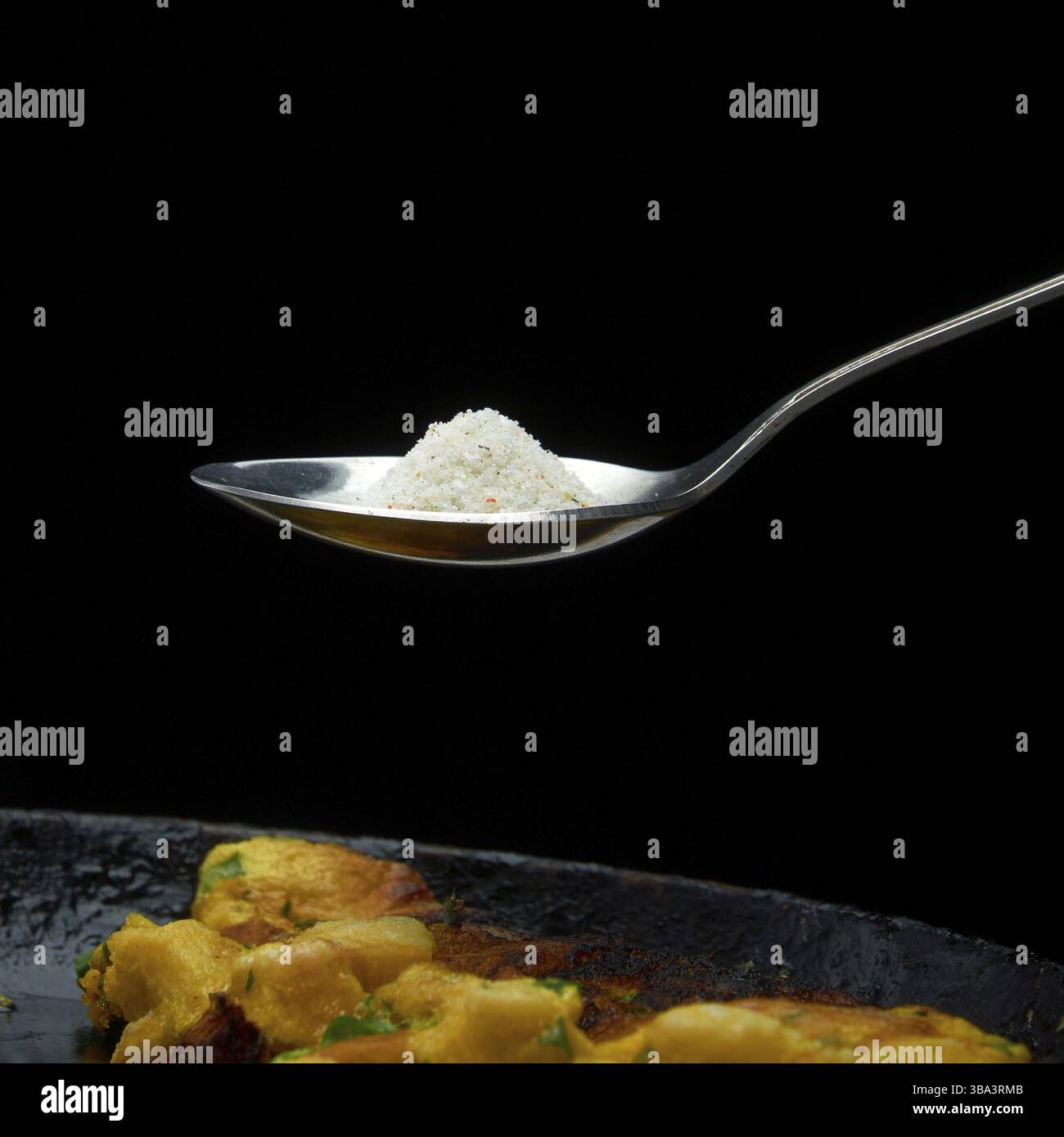 Un grande cucchiaio di sale intorno la pentola su uno sfondo scuro Foto Stock