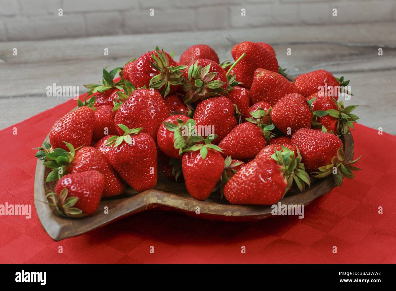 Primo piano, fragole su recipiente in legno intagliato, tovaglia rossa sotto, Liptovsky Hradok, Slovacchia, Europa Foto Stock