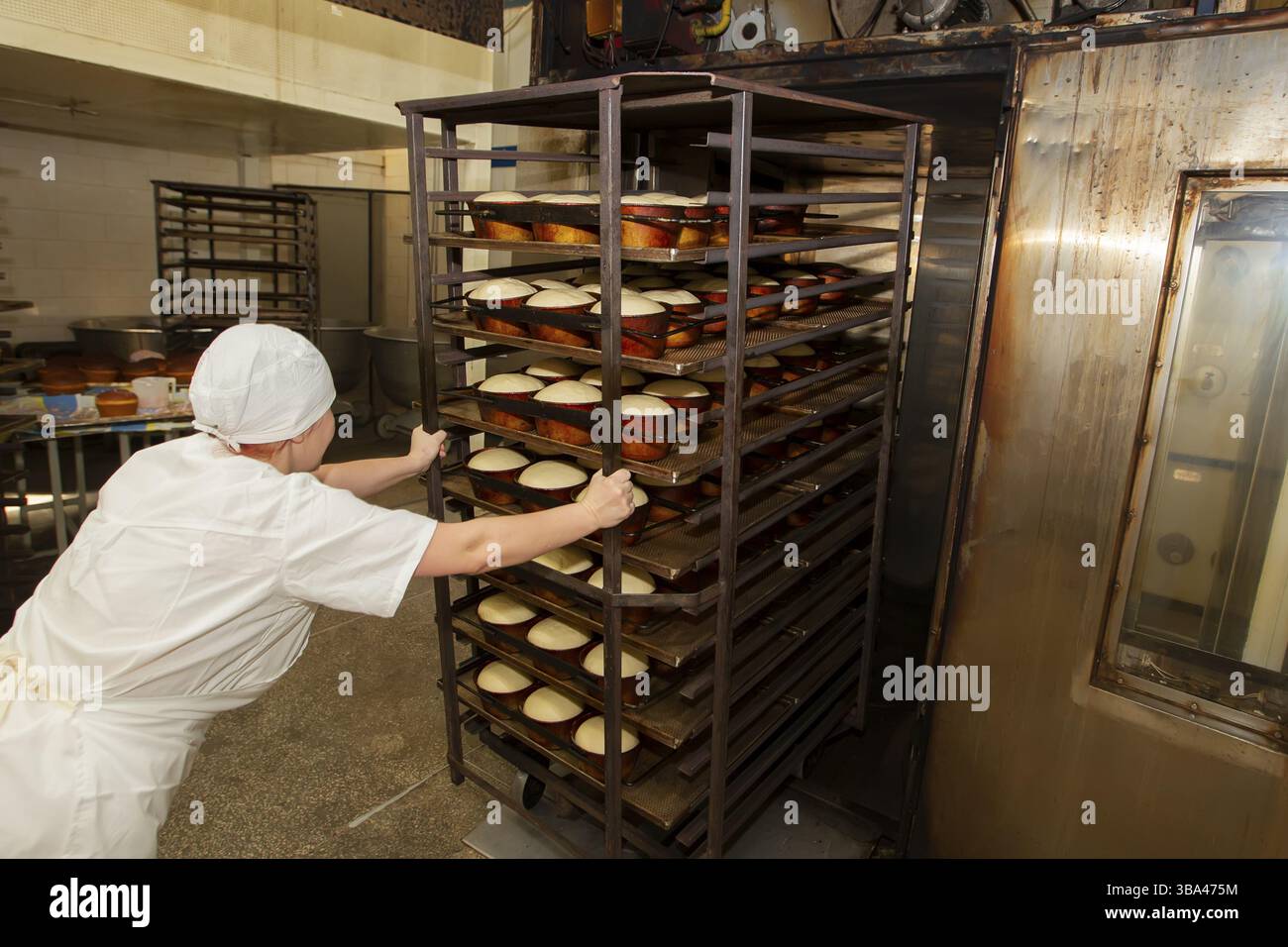 Bielorussia, la città di Gomil, 25 aprile 2019. Panetteria. Un operaio della panetteria mette dei vassoi con pane crudo nel forno. Produzione industriale di prodotti da forno, Foto Stock