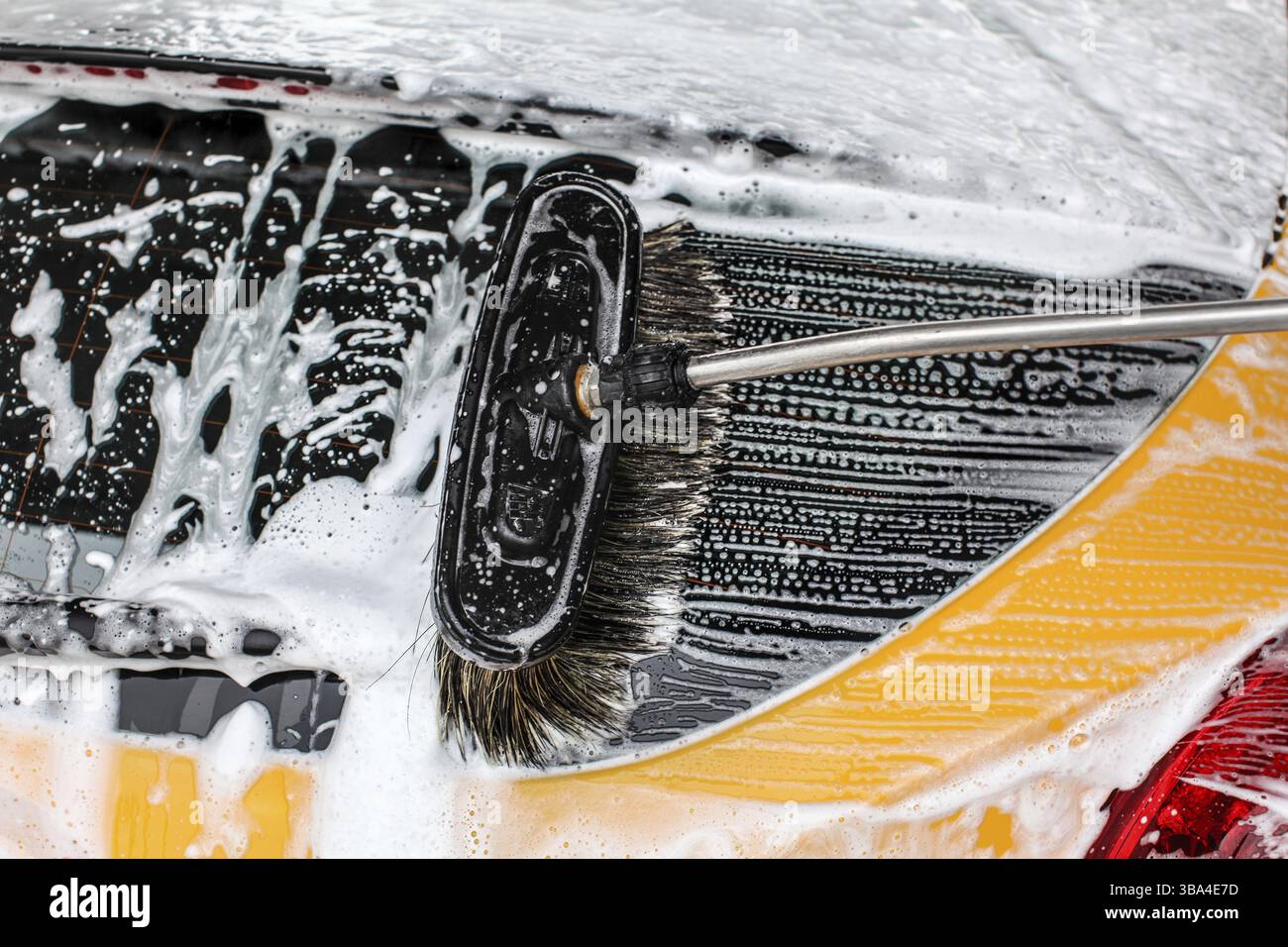 Dettaglio del finestrino posteriore giallo scuro dell'auto lavato in lavatrice. Spazzolare lasciando le pennellate con sapone bianco e schiuma di shampoo Foto Stock Dettaglio del finestrino posteriore giallo scuro dell'auto lavato in lavatrice. Spazzolare lasciando le pennellate con sapone bianco e schiuma di shampoo Foto Stock